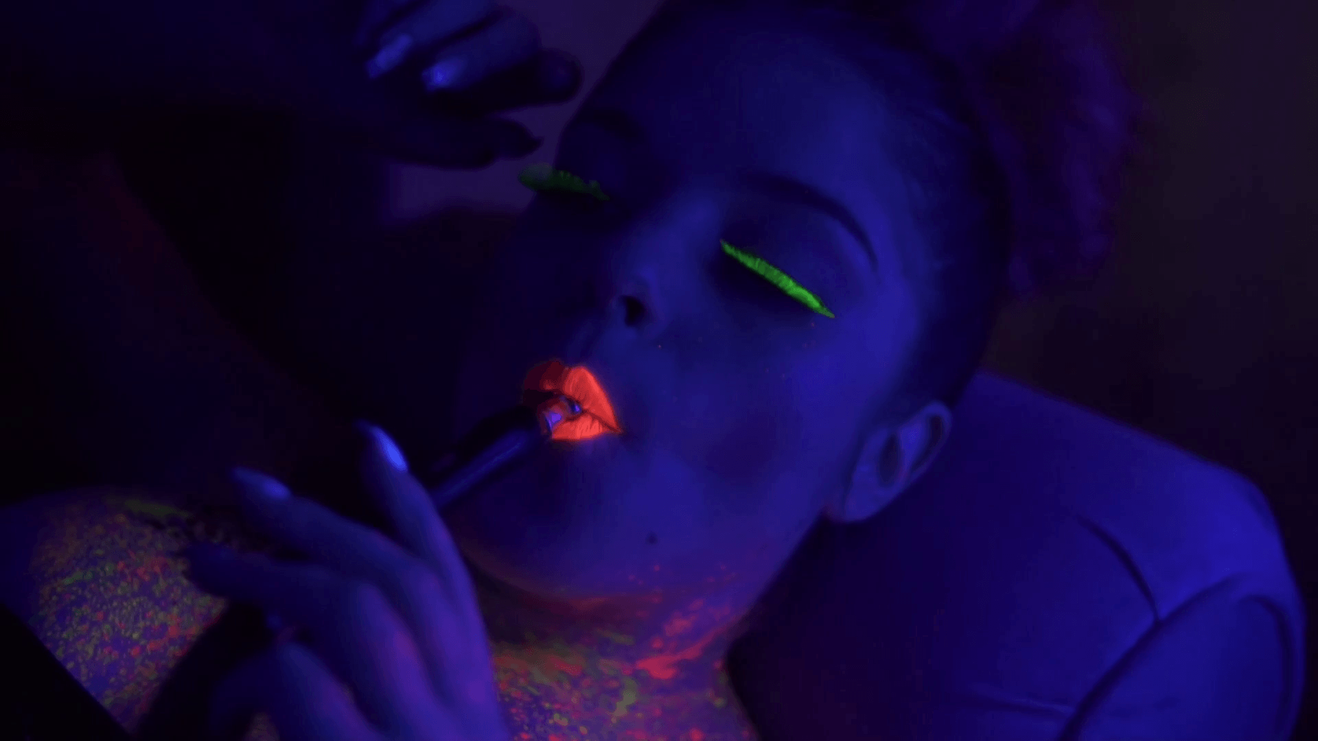 Portrait of a young beautiful woman with fluorescent makeup inhaling