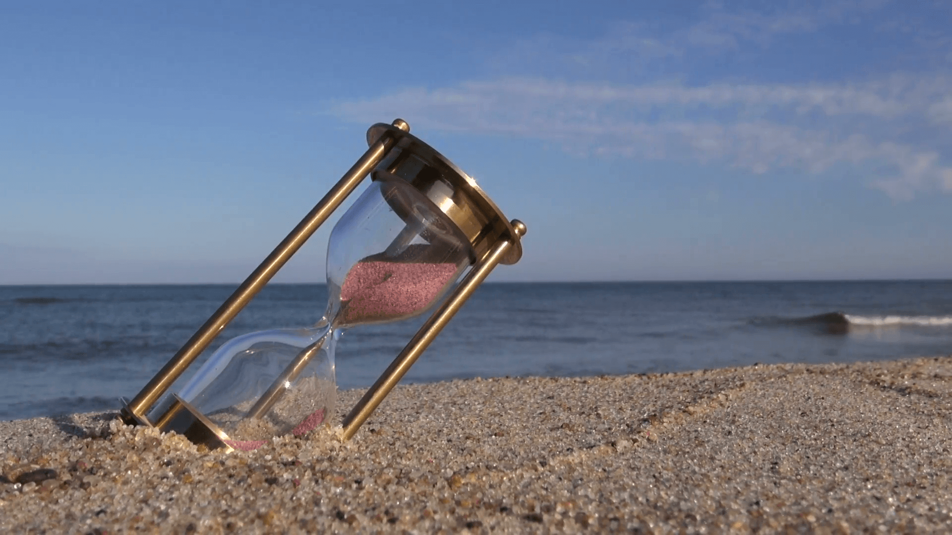 ancient brass sandglass hourglass on sea beach sand Stock Video