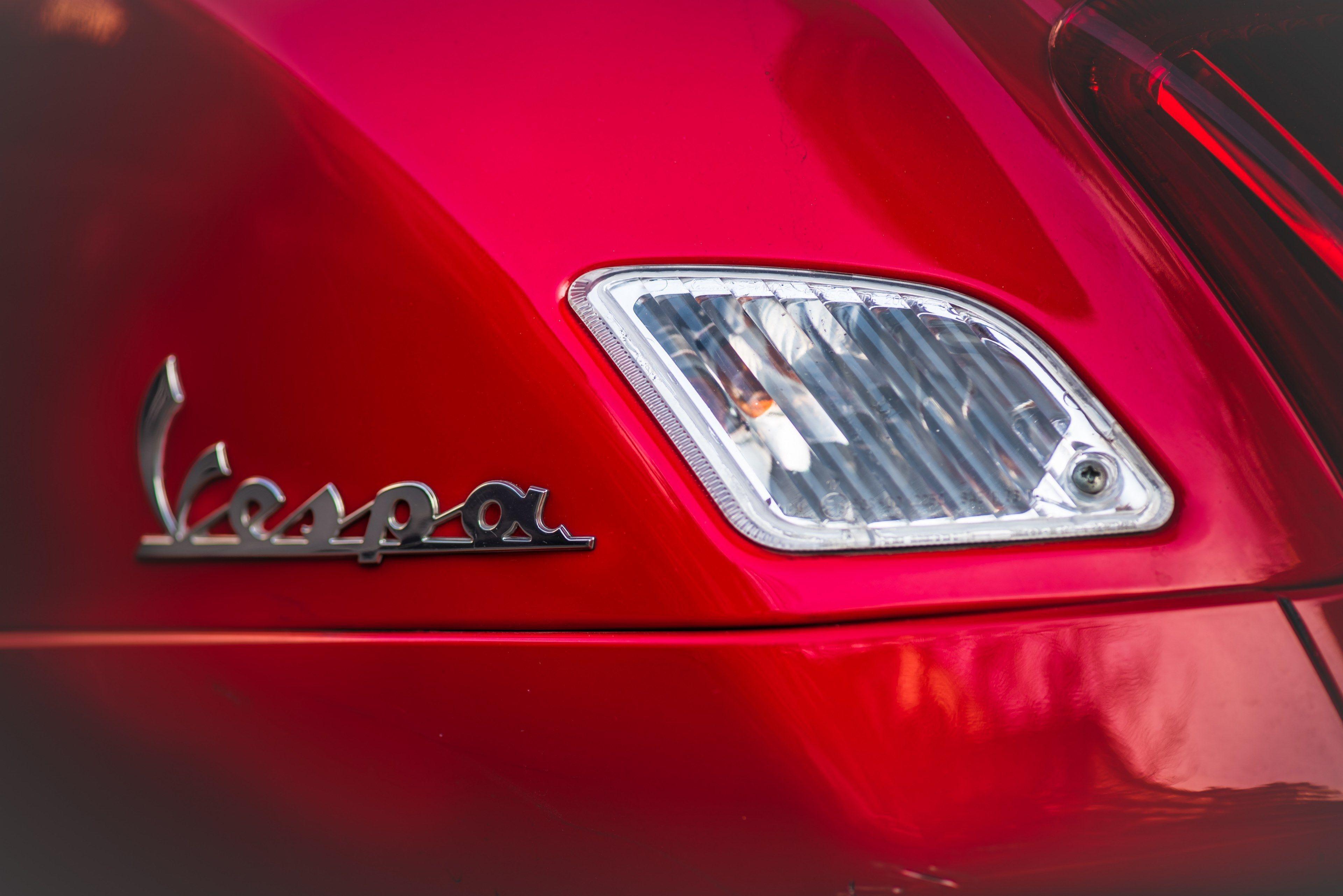 macro of a vespa logo on a red automobilevespa logo on a motor