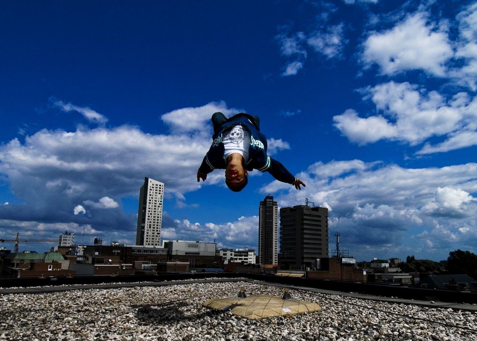 The guy doing parkour performs a backflip on the roof
