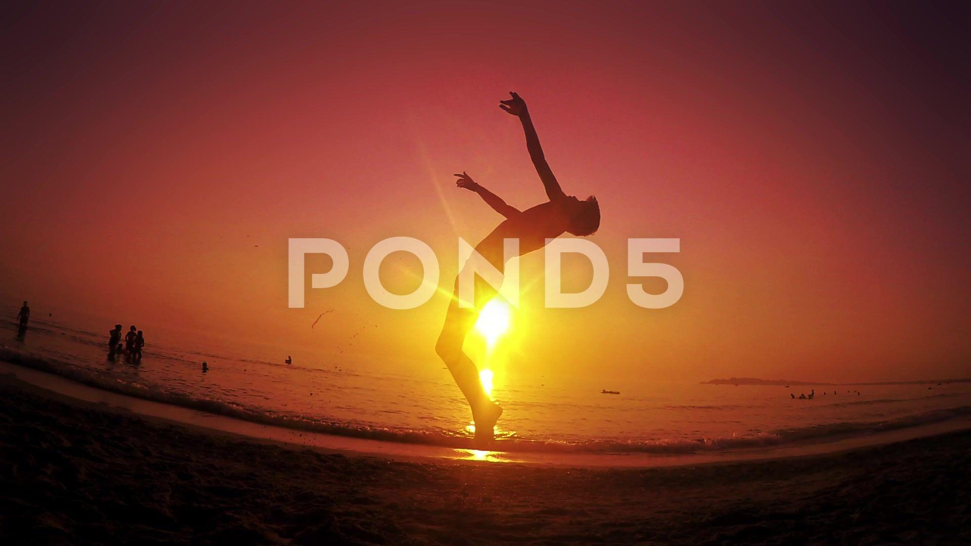 Parkour free runner runs and jumps backflip at summer beach sunset