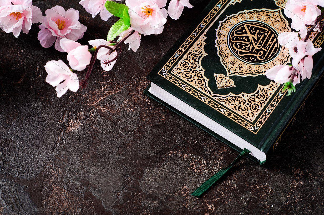 Islamic Book Koran and spring flowers brunch on dark background