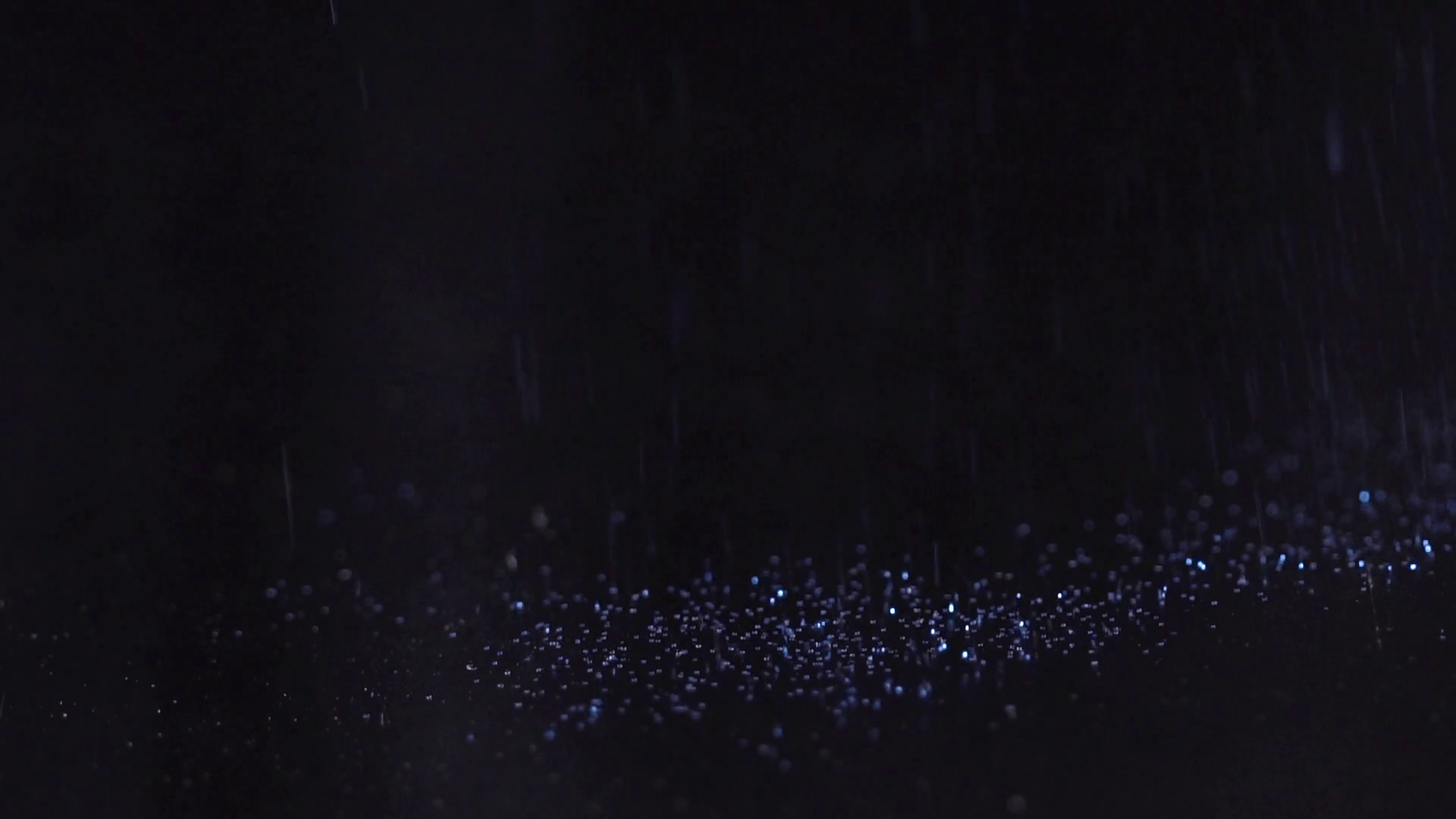 Blue sparkles falling on the black background, abstract slow motion