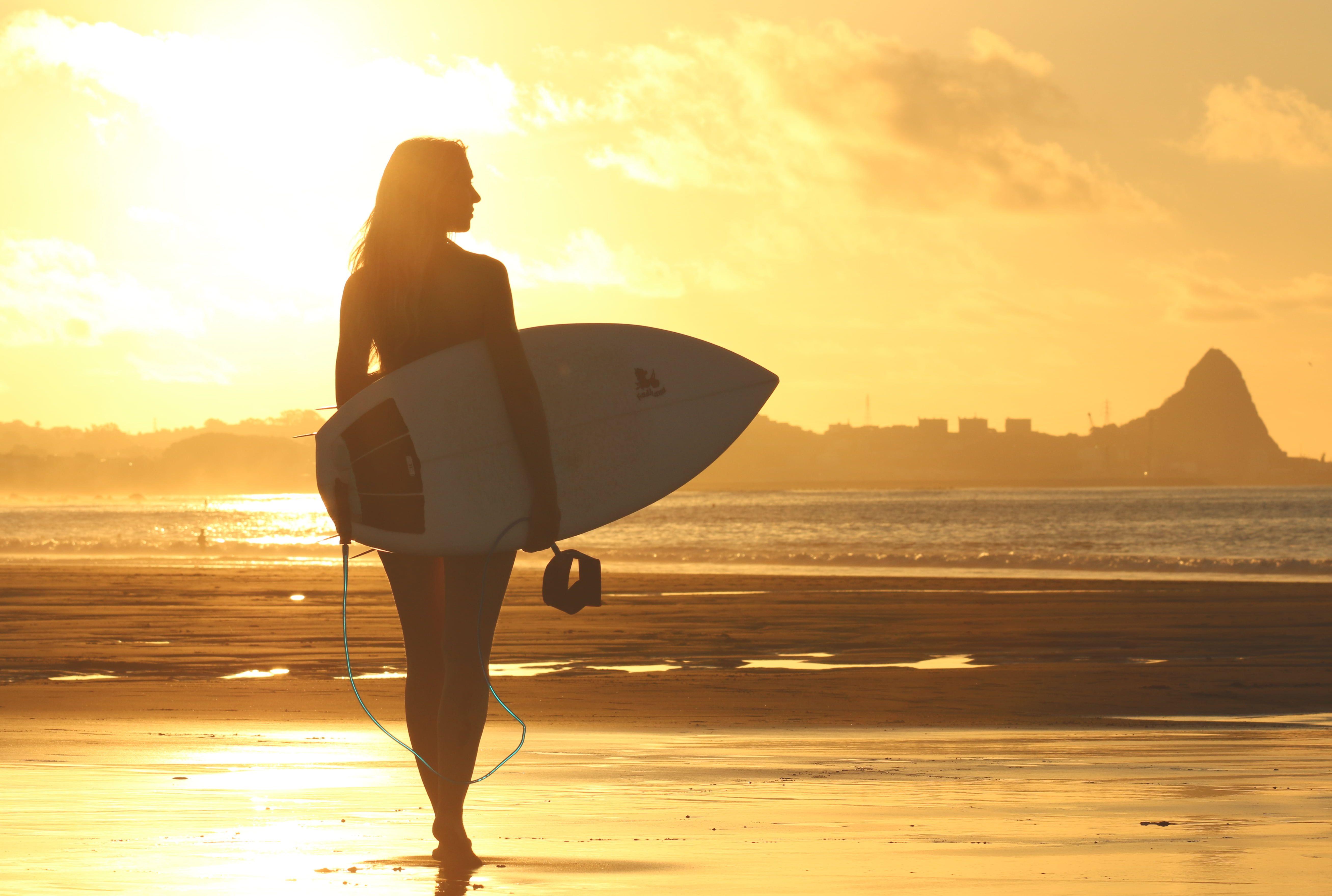 Woman Holding Surf Board Standing on Shoreline during Sunset HD