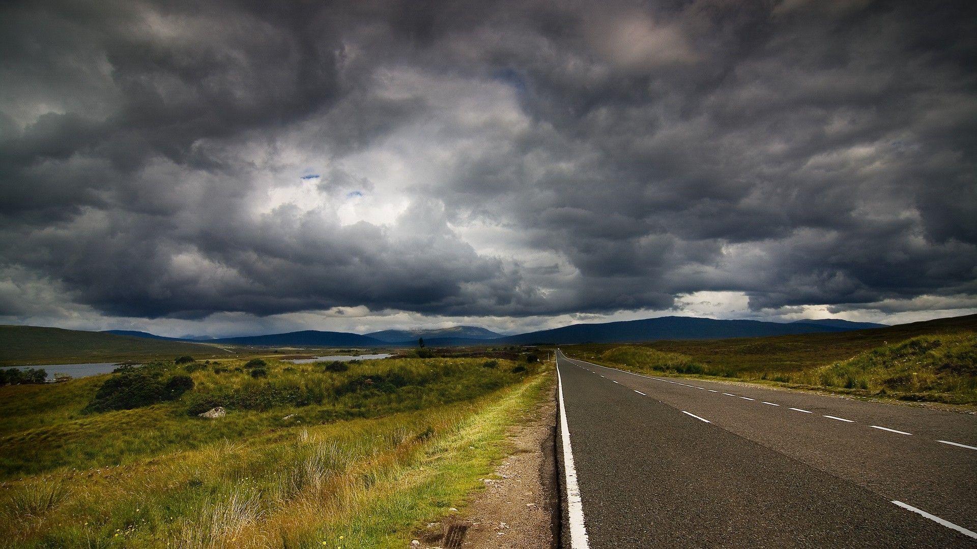 Highway among the fields under dark clouds wallpaper and image
