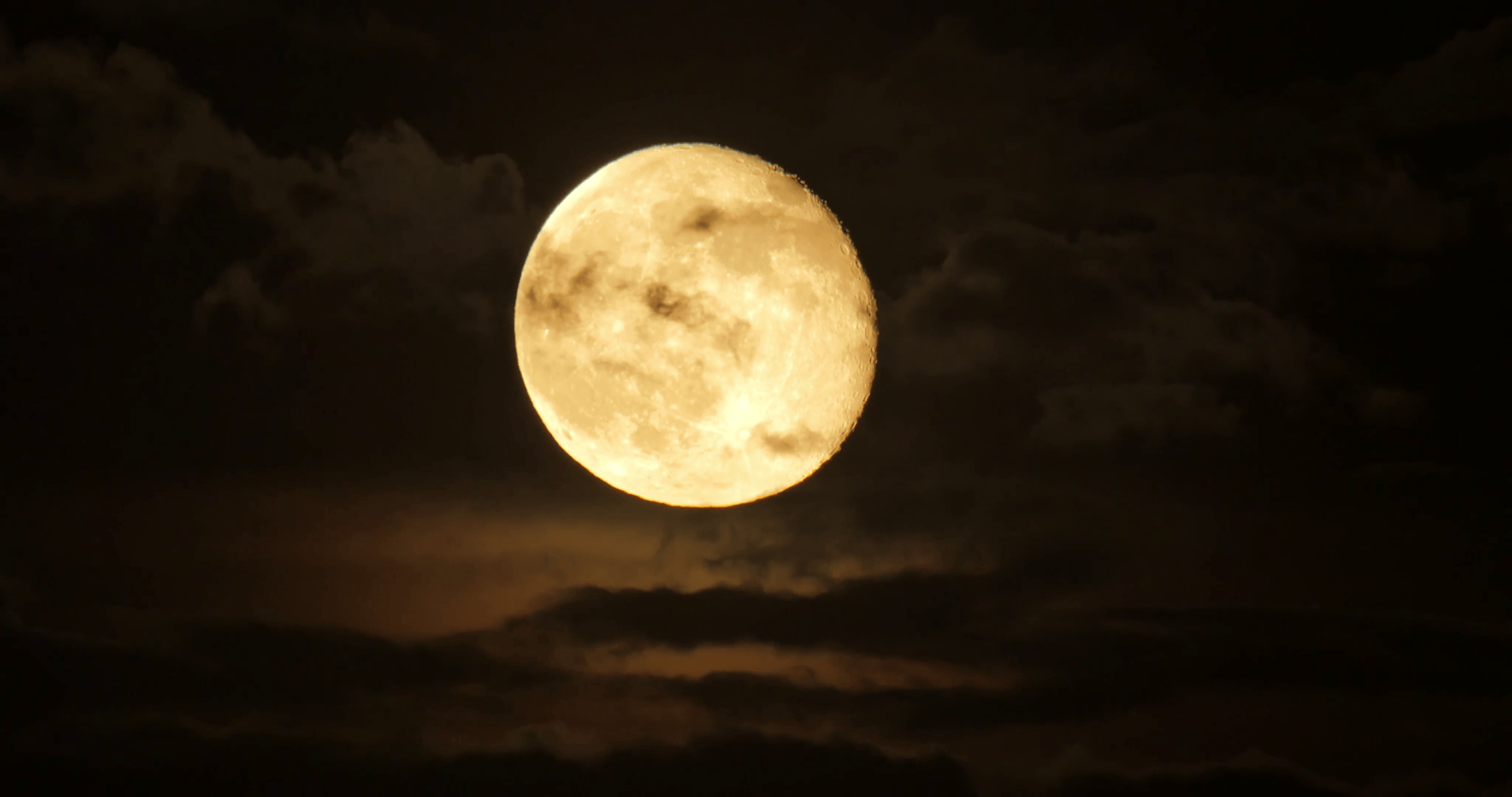 Beautiful full moon shining through moving clouds background at