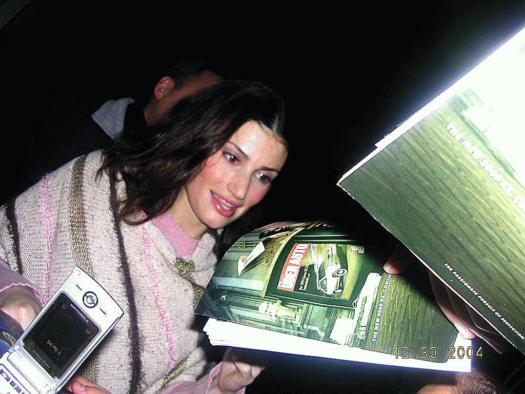 Idina Menzel smiling as she signs her fans playbills and posters 12