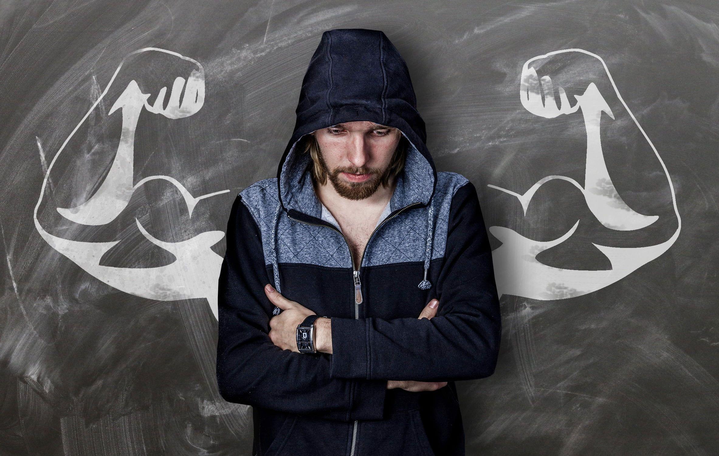 Man in blue hoodie jacket with biceps of man's drawing behind him HD