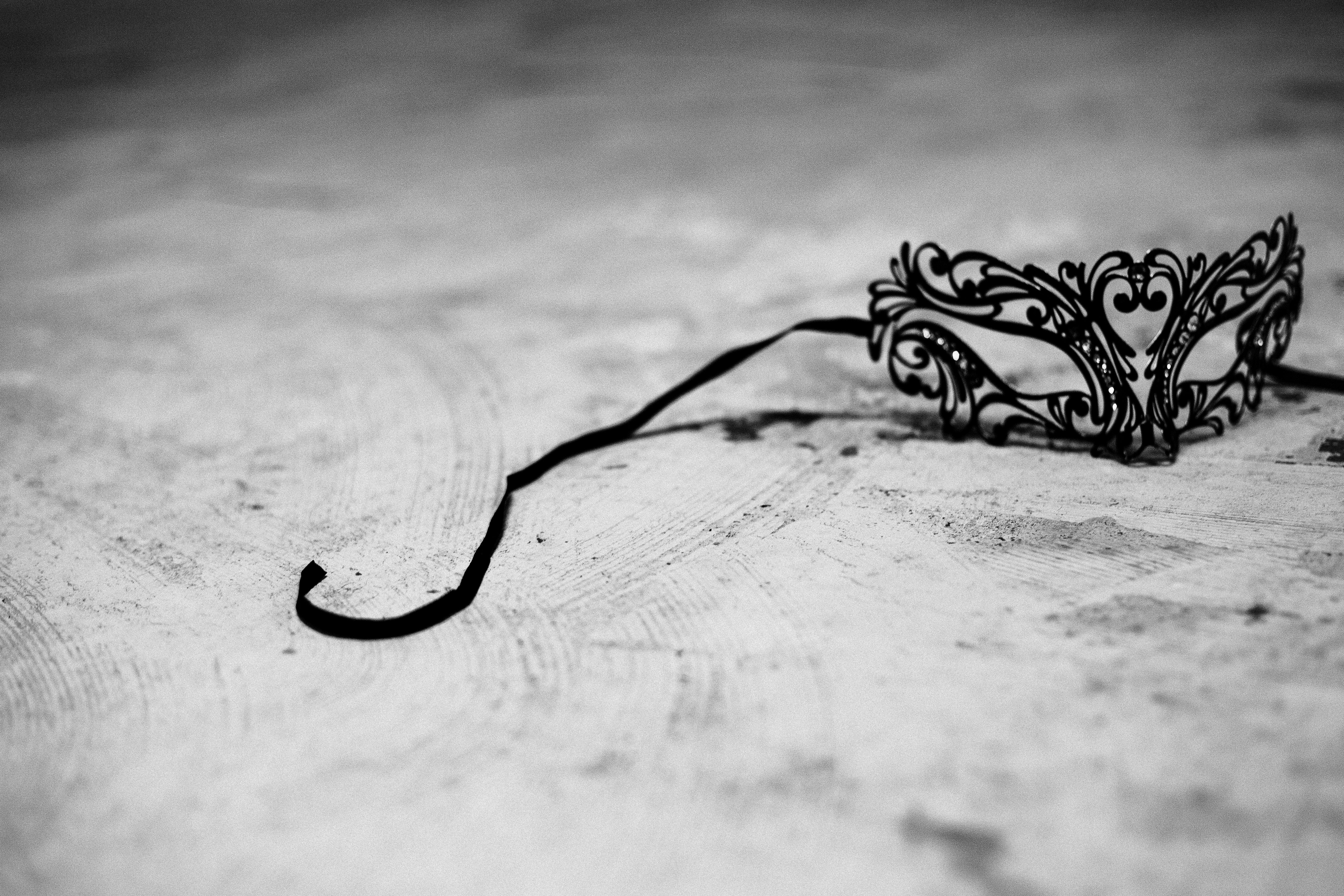 greyscale photography of black masquerade mask on concrete surface