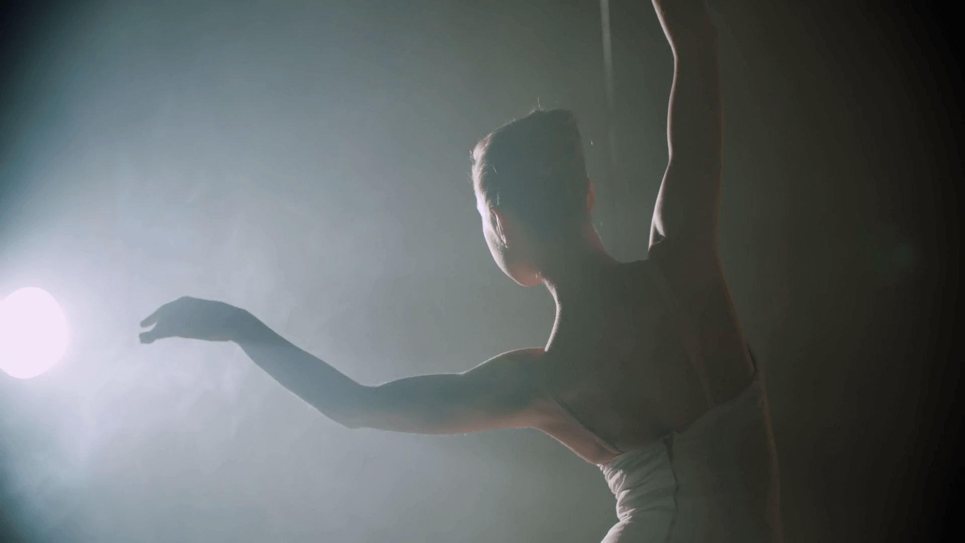 graceful ballerina dancing elements of classical ballet in the dark with light and smoke on the background, slow motion Stock Video Footage