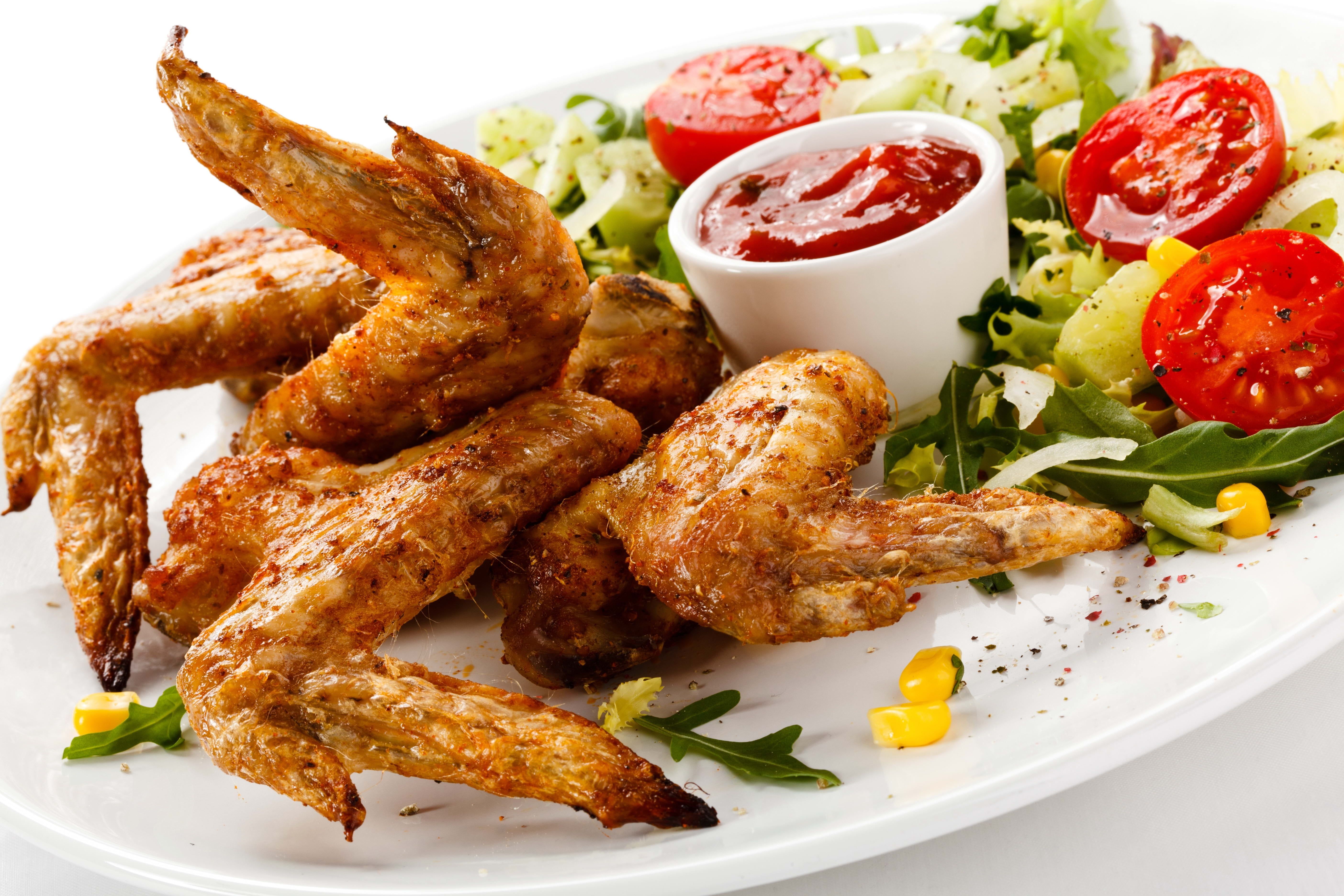 Food photography of fried chicken wings with sauce served on white