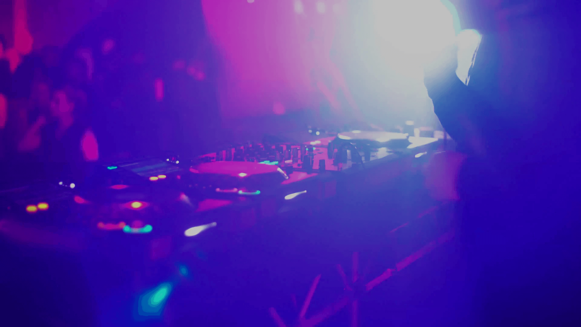 DJ disk jockey mixing songs at his desk turntable in nightclub. Two