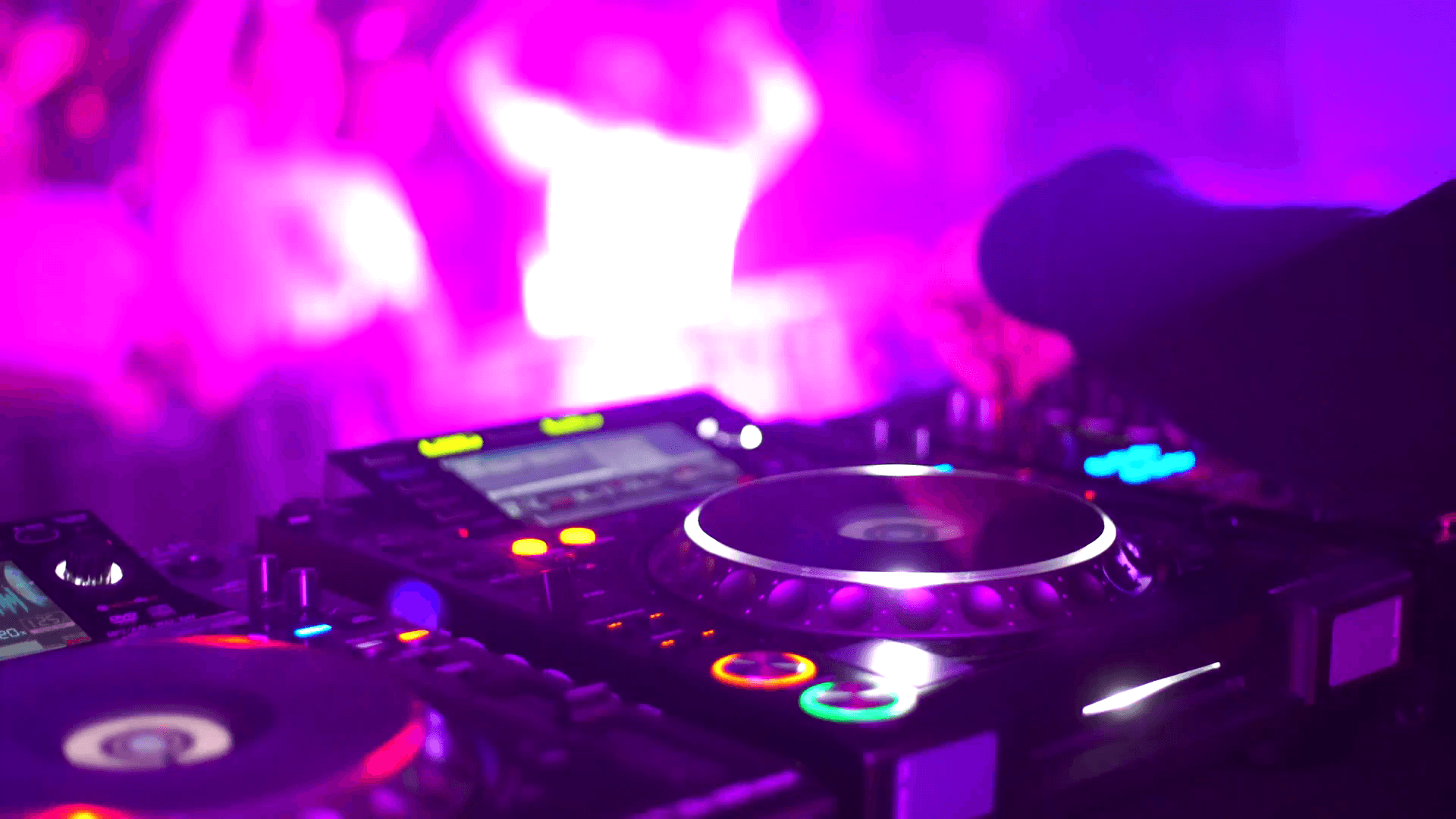 DJ disk jockey mixing songs at his desk turntable in nightclub. Two