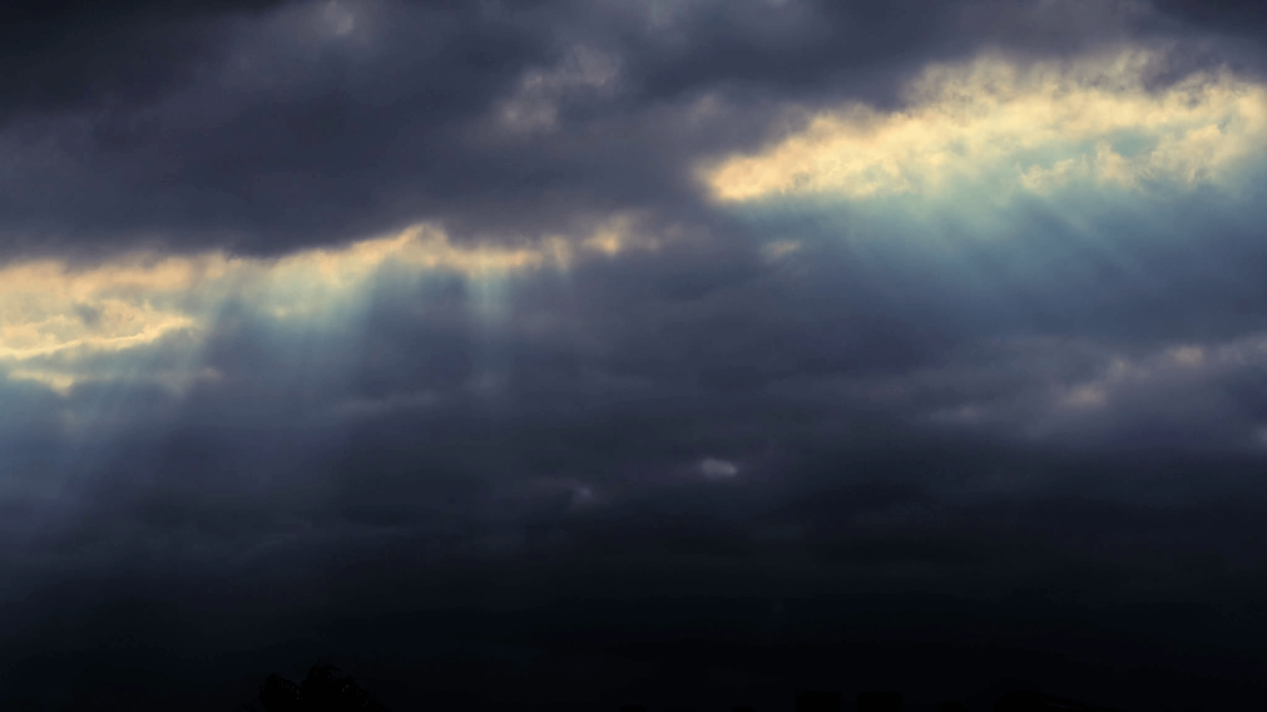 Sunlight rays shining through dramatic rain storm clouds background