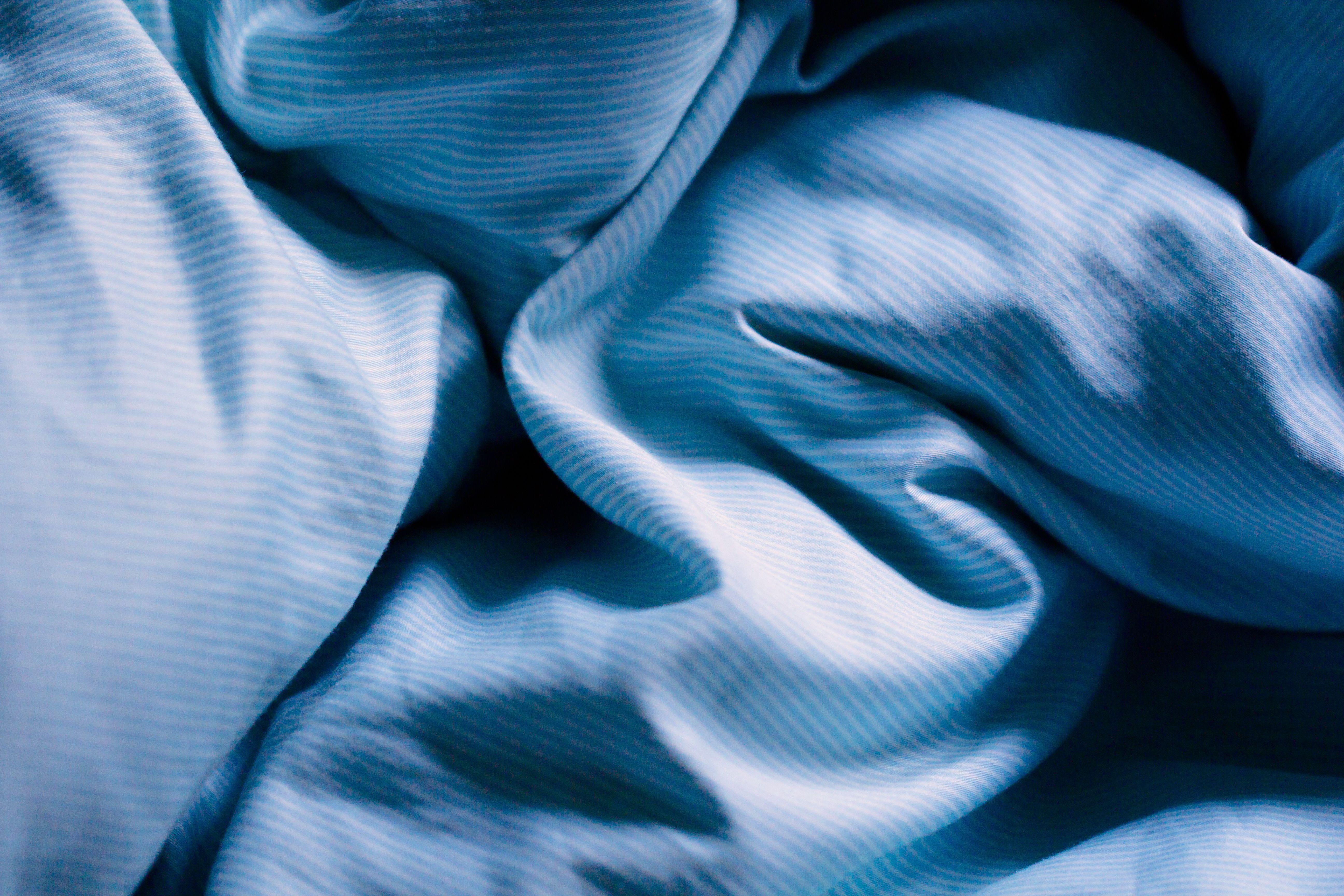 Wrinkled blue bed sheets on a morning as a background. Blue Lights