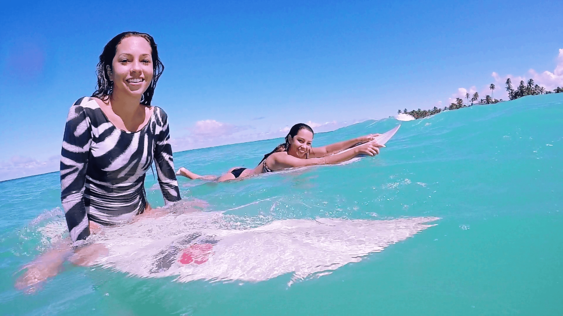 Two Beautiful Happy Brazilian Surf Girls Laying On Surfboard Smiling