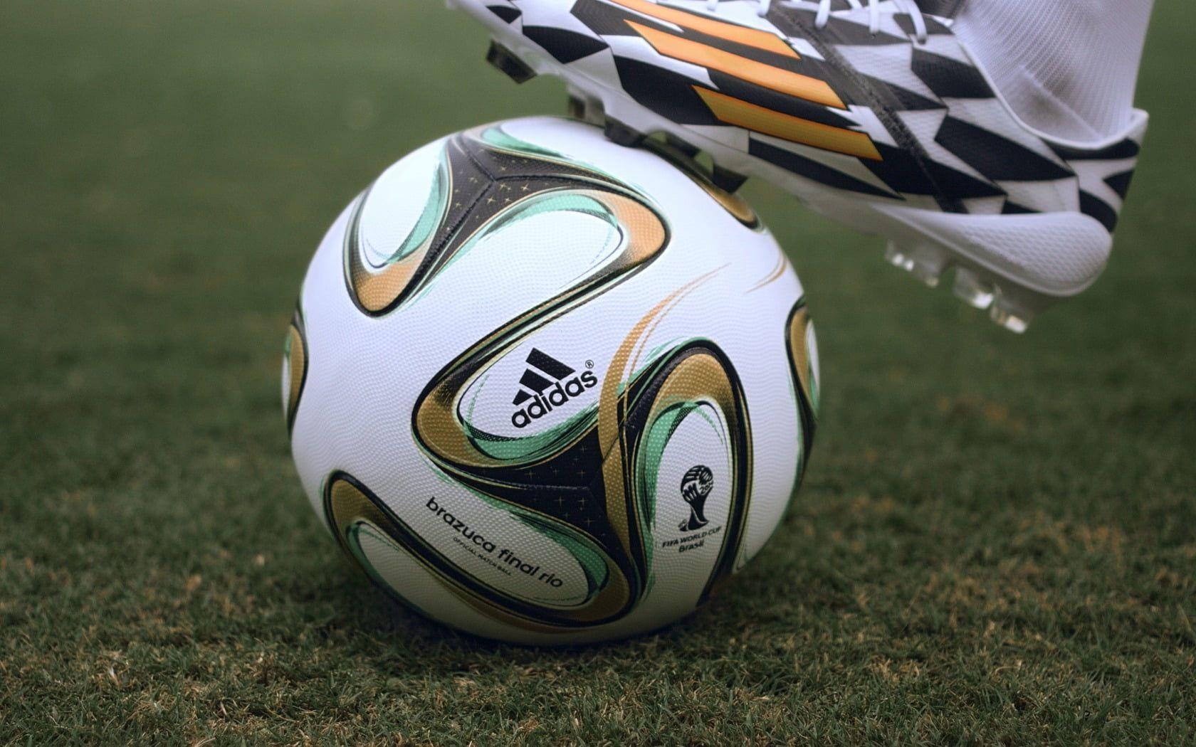 White, brown, teal, and black Adidas soccer ball on green grass