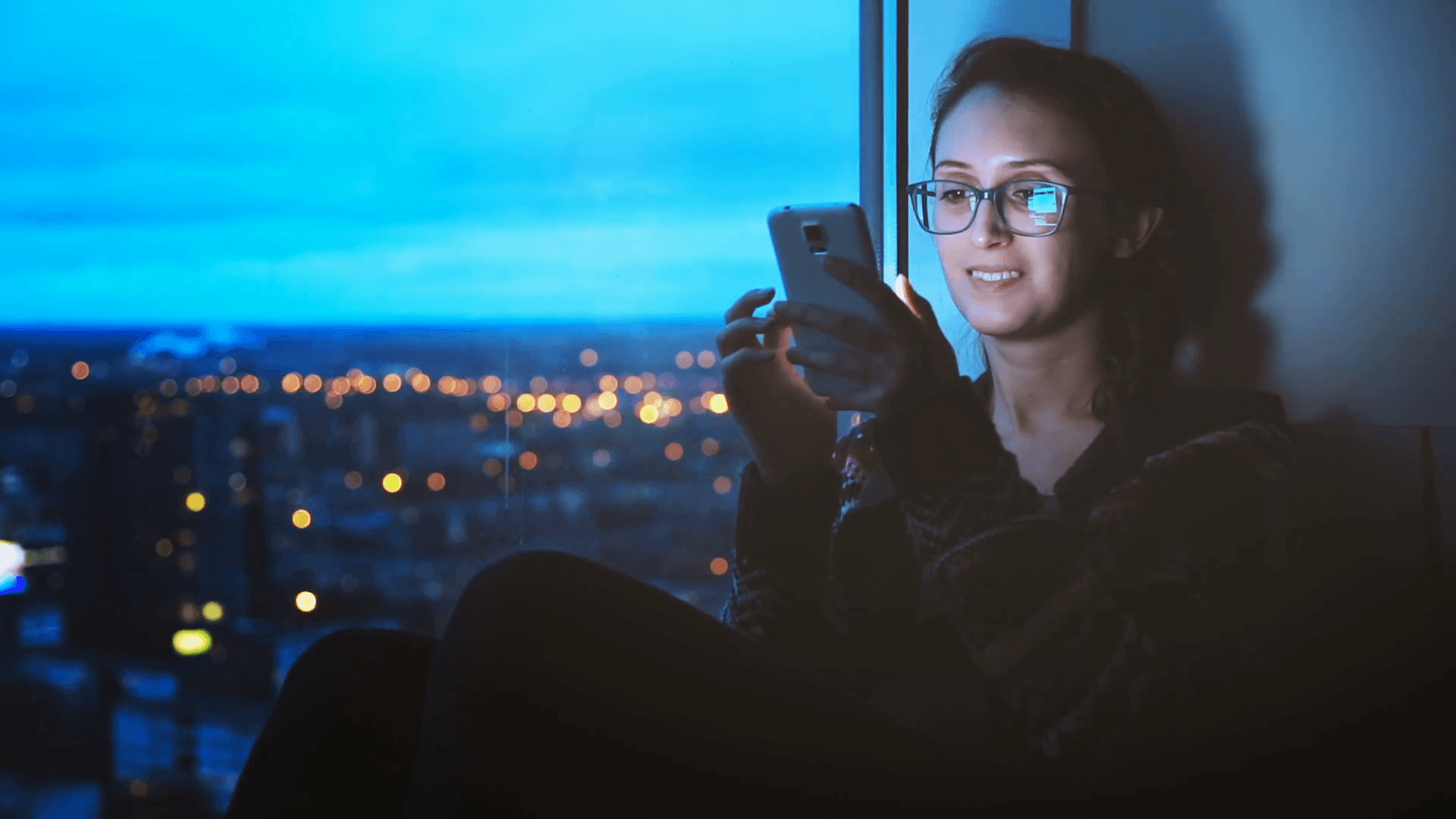 Young Woman Texting on Smartphone on Night City Lights Background