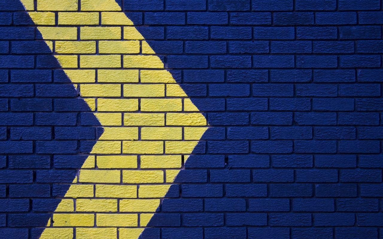 Download wallpaper 1280x800 wall, brick, arrow, blue, yellow