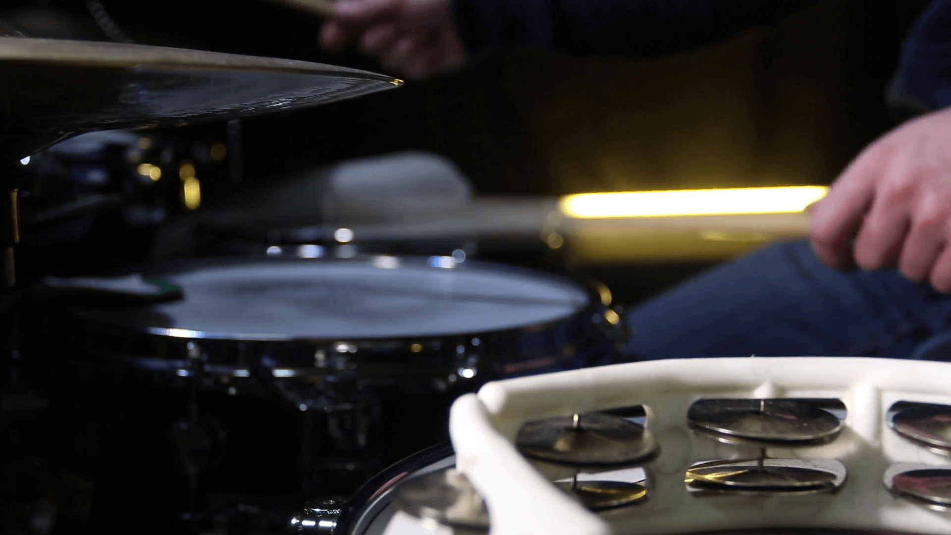 Close up of drum tambourine and a drummer playing on drums