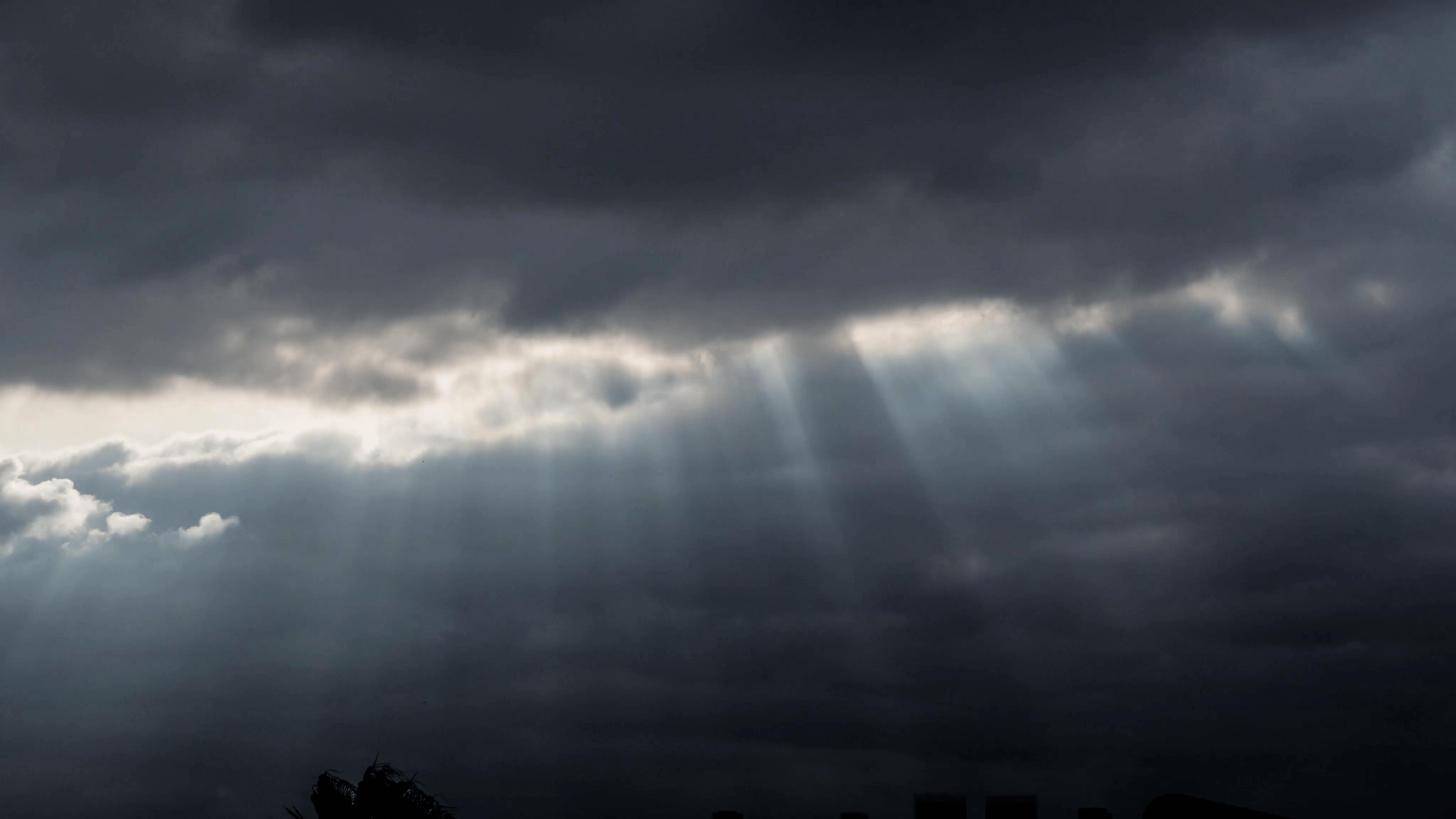 Rays of sunlight shining through rainy storm clouds background. 4K