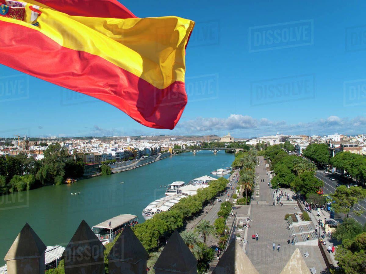 Spanish flag fluttering with city and river in background, Seville