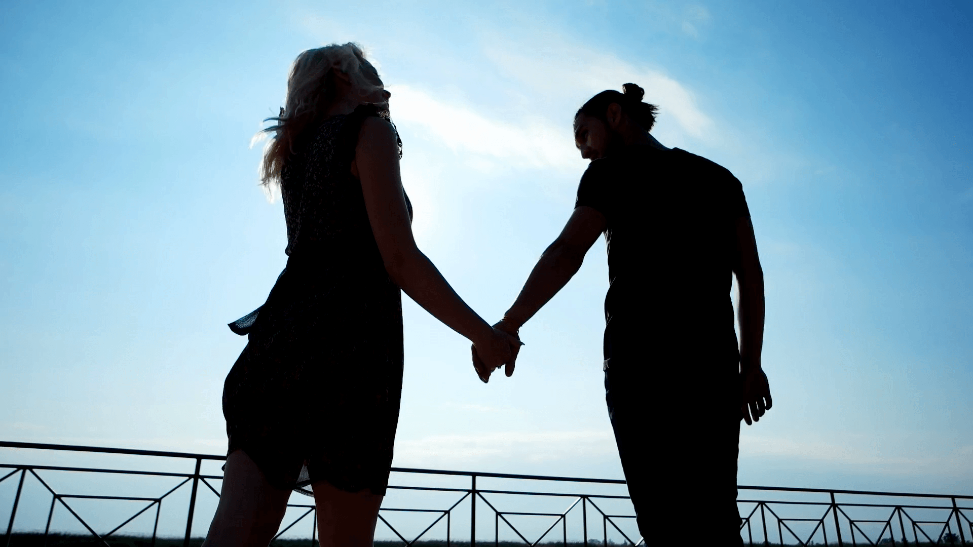sweet couple walking in sunlight holding each other hand, wind