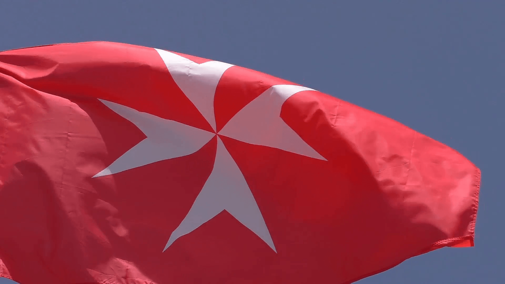 Close up of white Maltese cross on red background flag, the national
