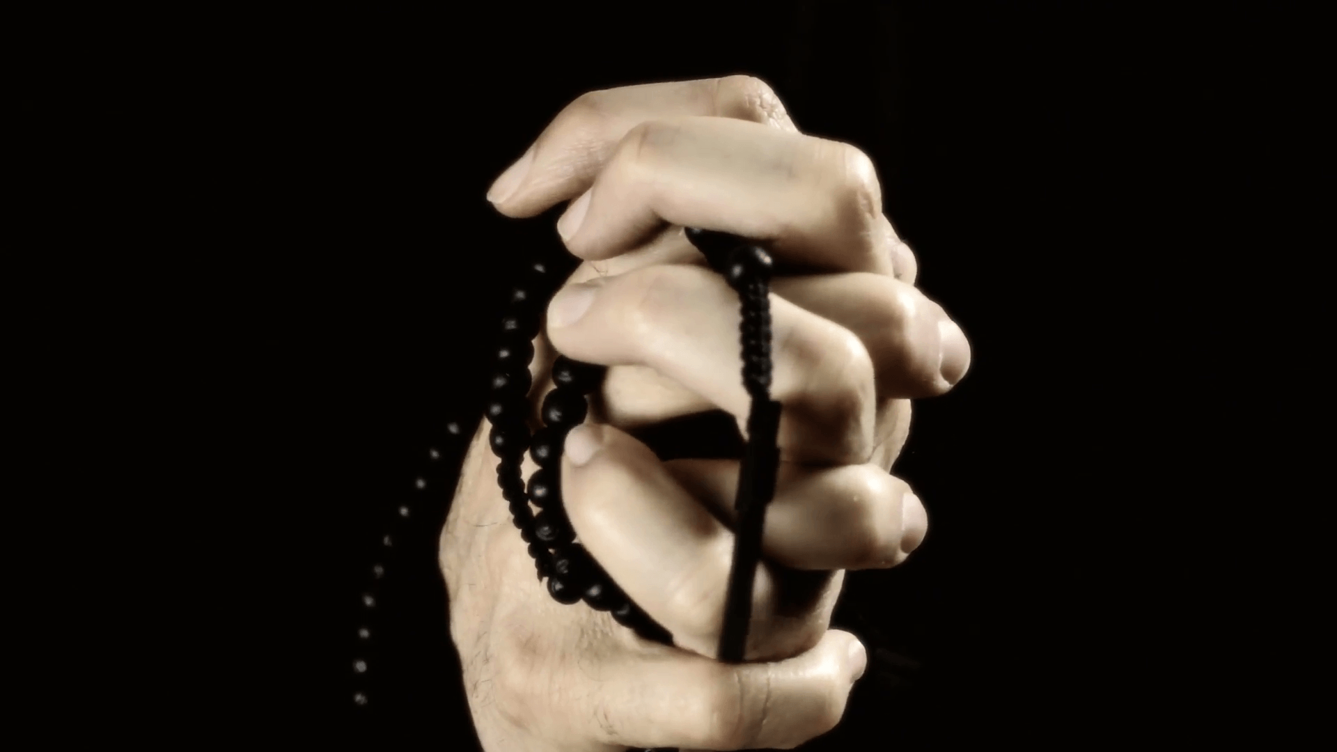 Hands praying black rosary. The wrinkled hands of an old man holding