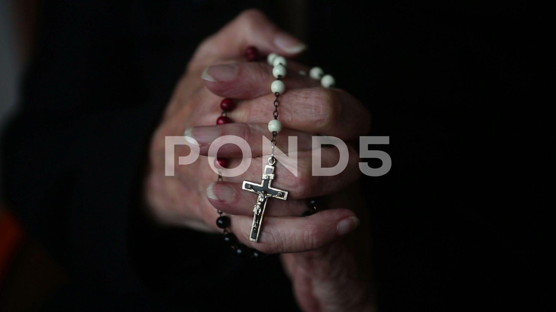 Closeup of old woman's hands praying and holding a rosary Footage