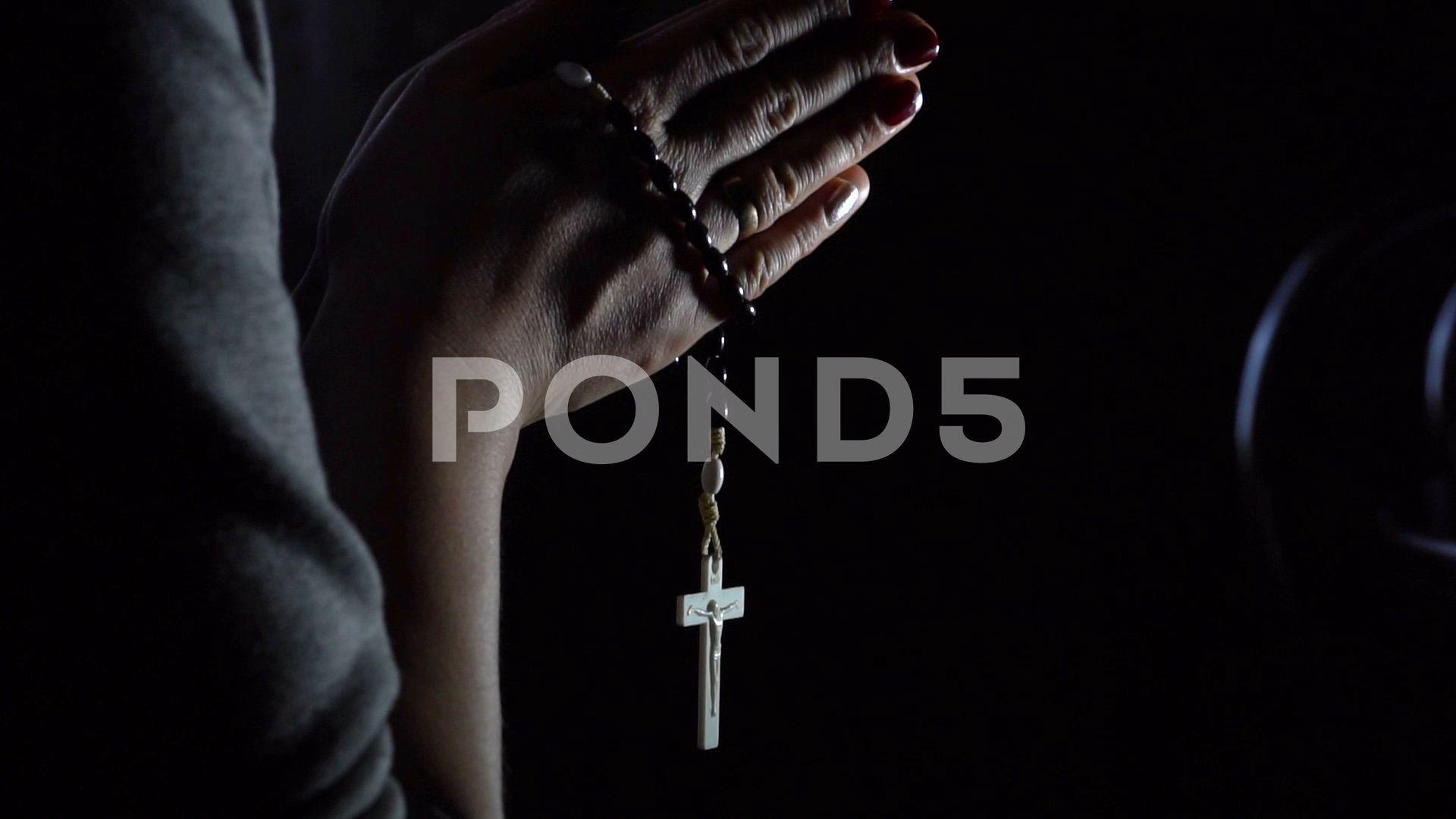 Woman hands holding rosary on black background Clip