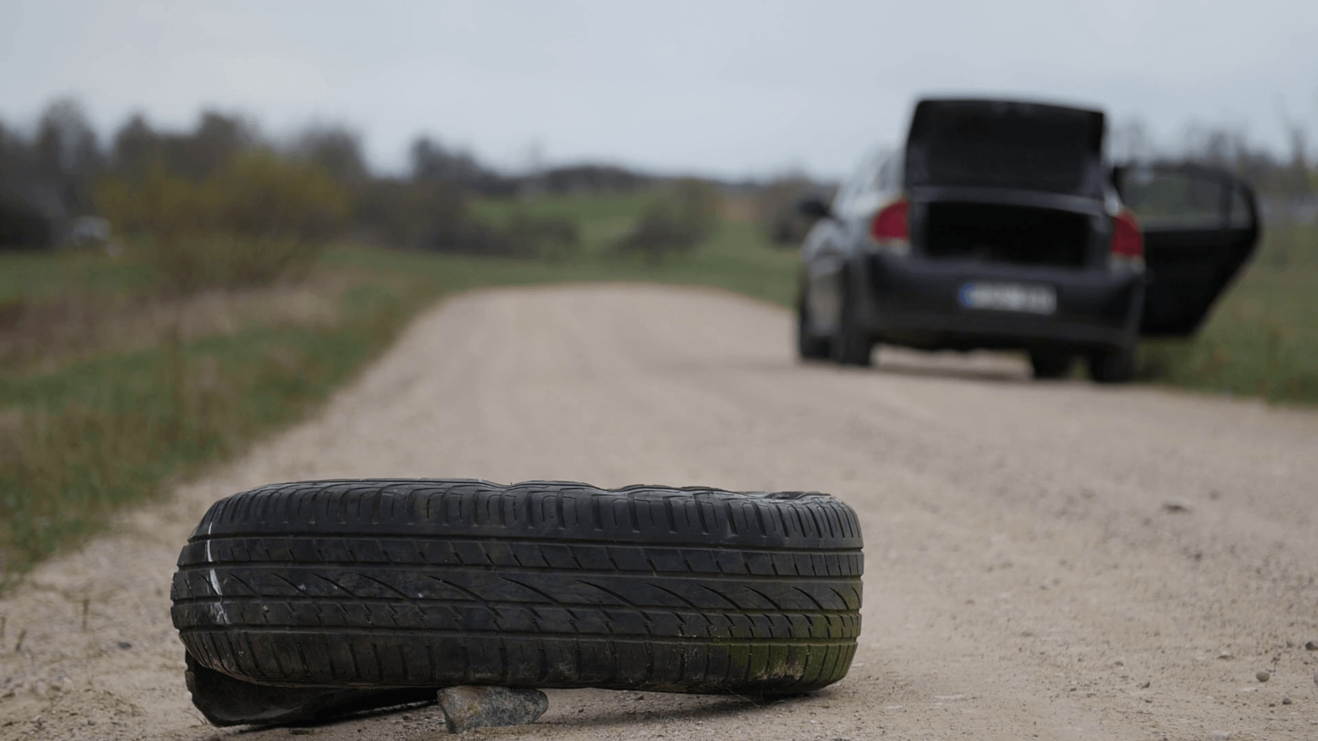 Used old tire eliminated at roadside. Black car in the background