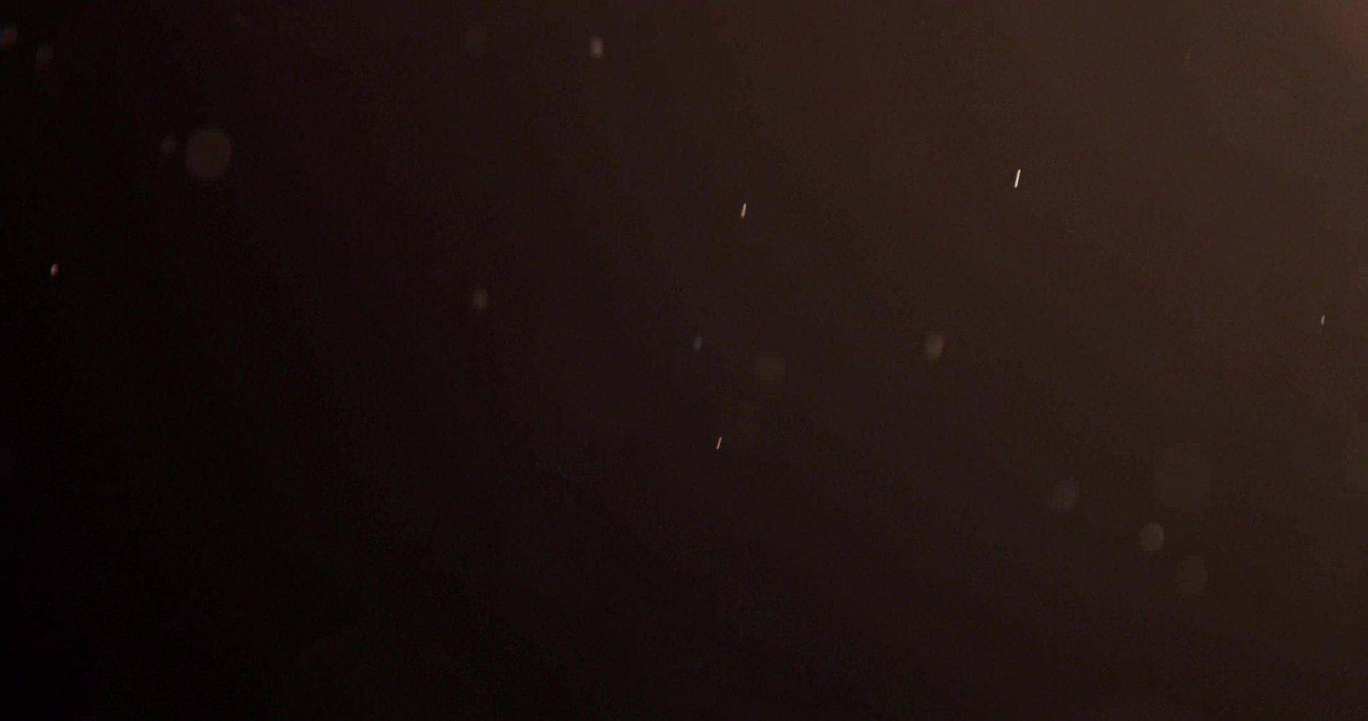 White particles floating with random movements on dark background