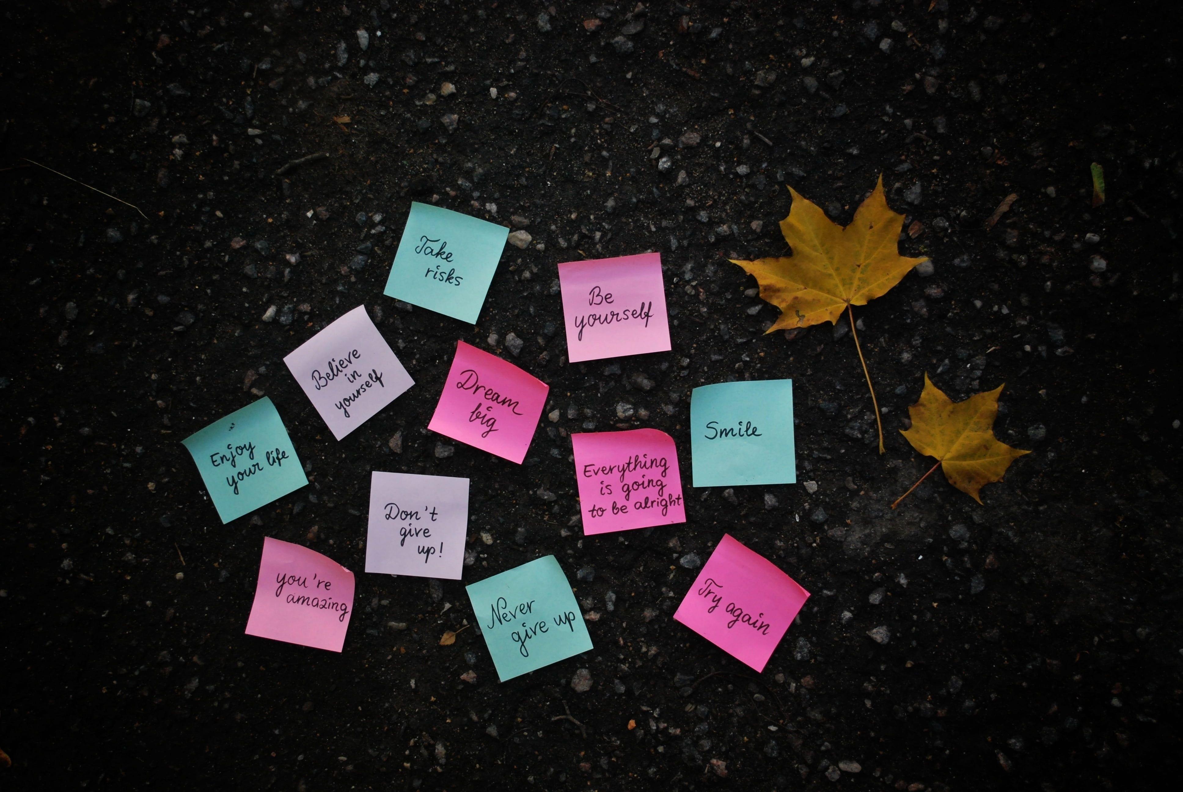 Assorted colored printed sticky notes on black concrete floor HD