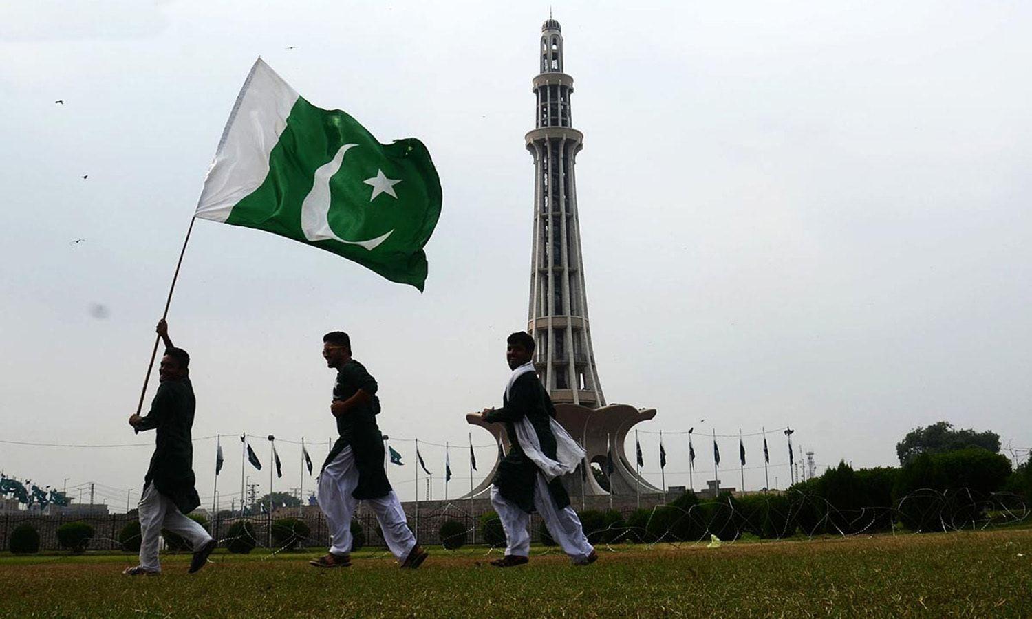 People holding national flag at Minar e Pakistan in connection to