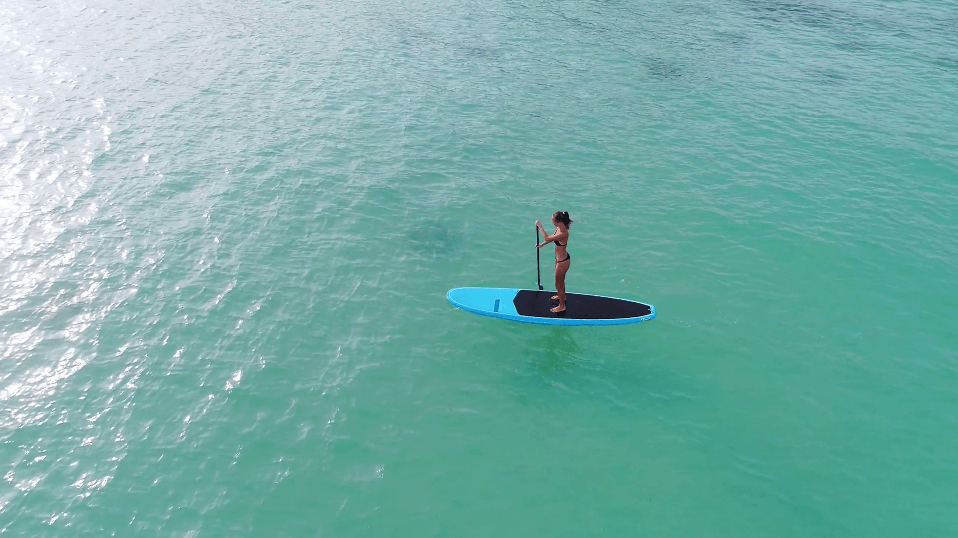 Aerial drone bird's eye view of man exercising sup paddle board