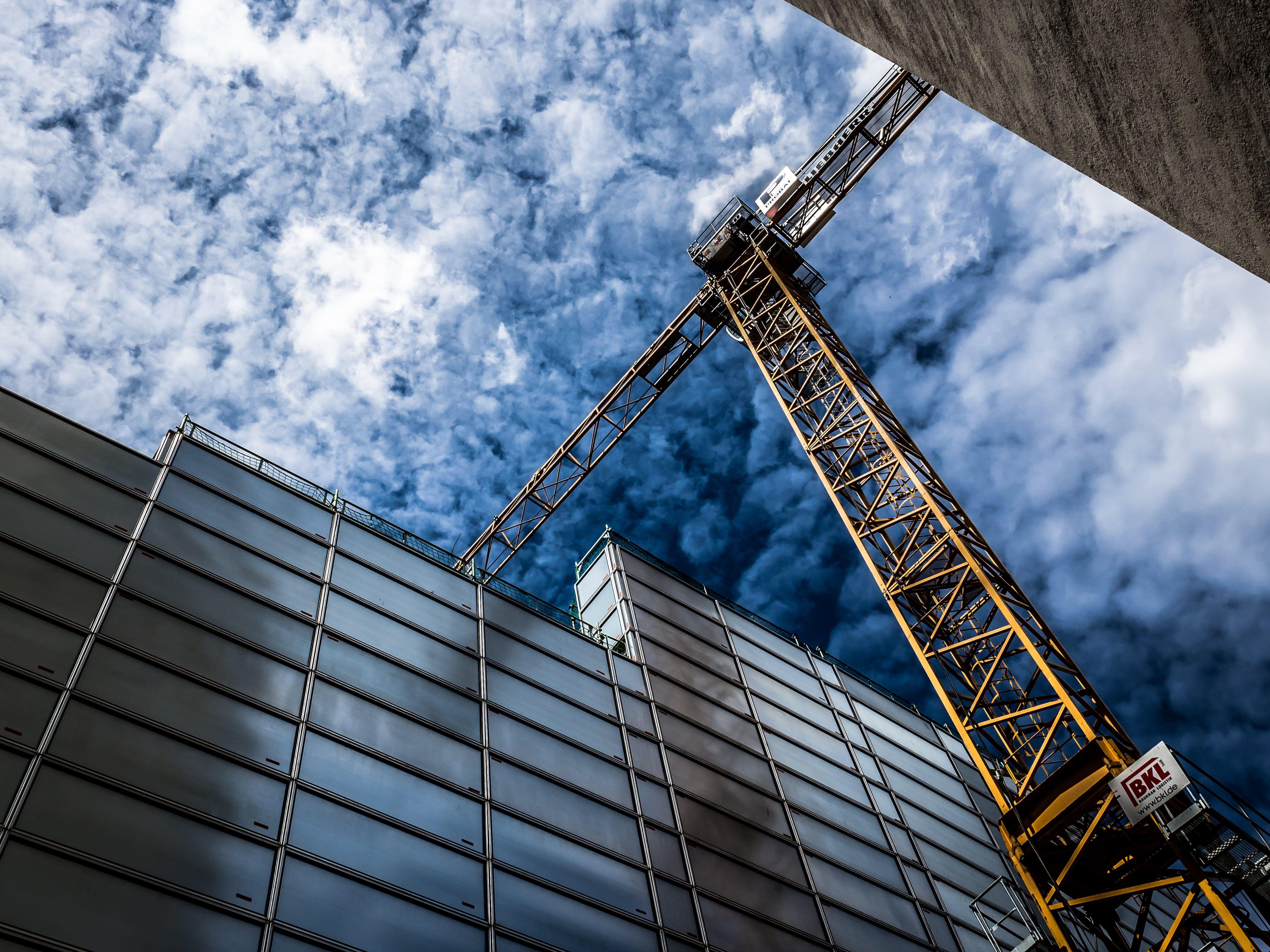 Yellow steel crane beside of glass building HD wallpaper. Wallpaper