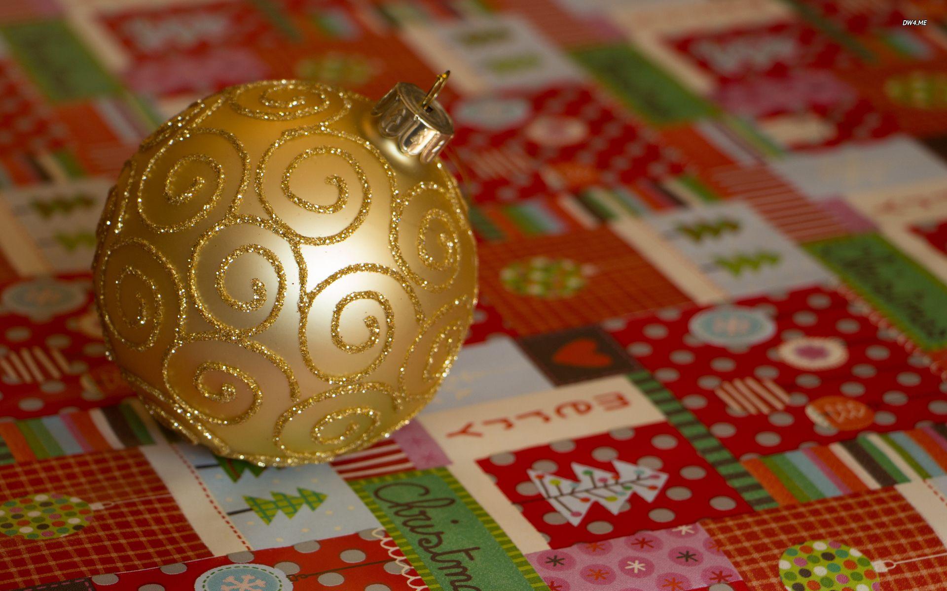 Golden bauble on Christmas wrapping paper wallpaper