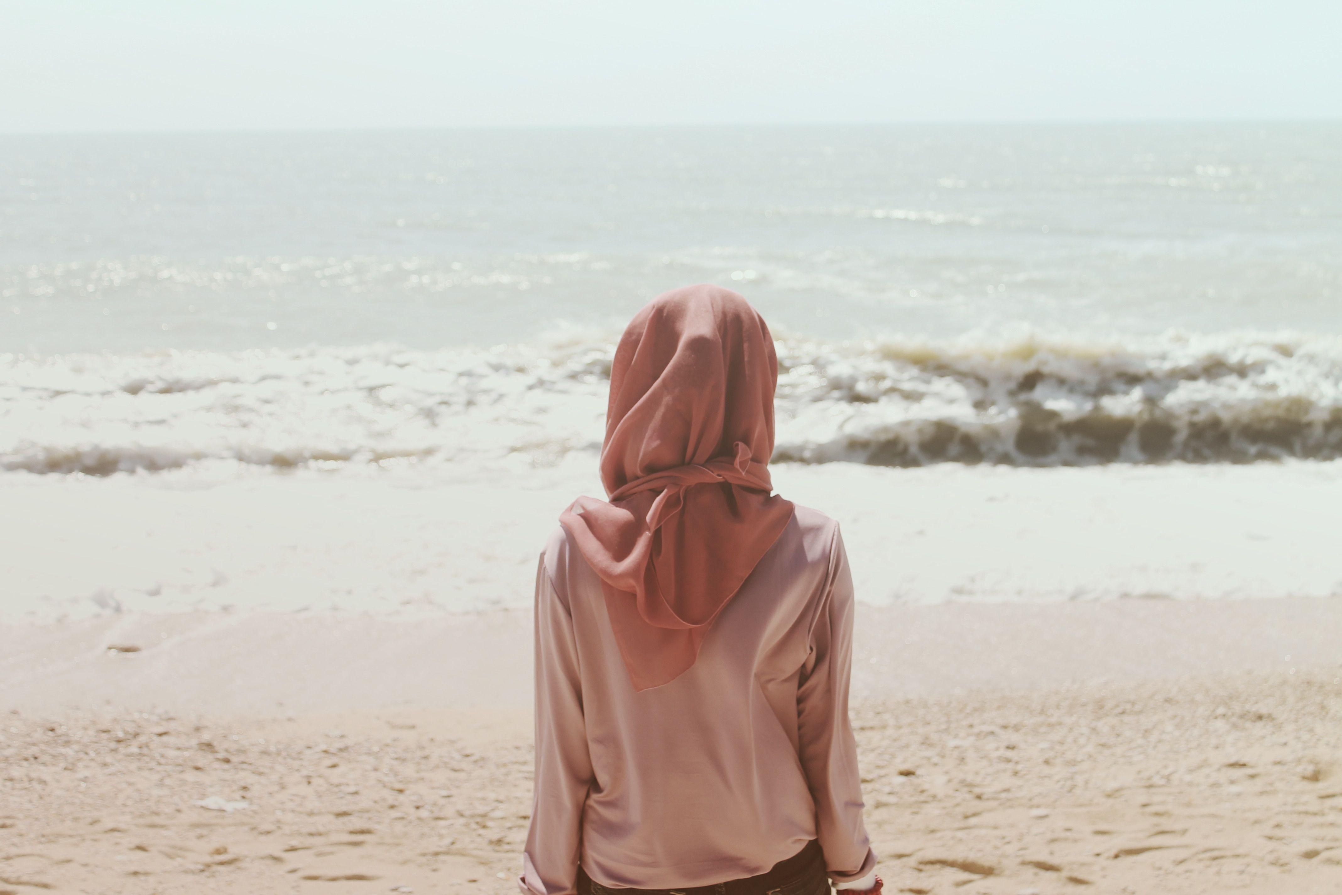 woman in pink hijab near ocean during daytime free image