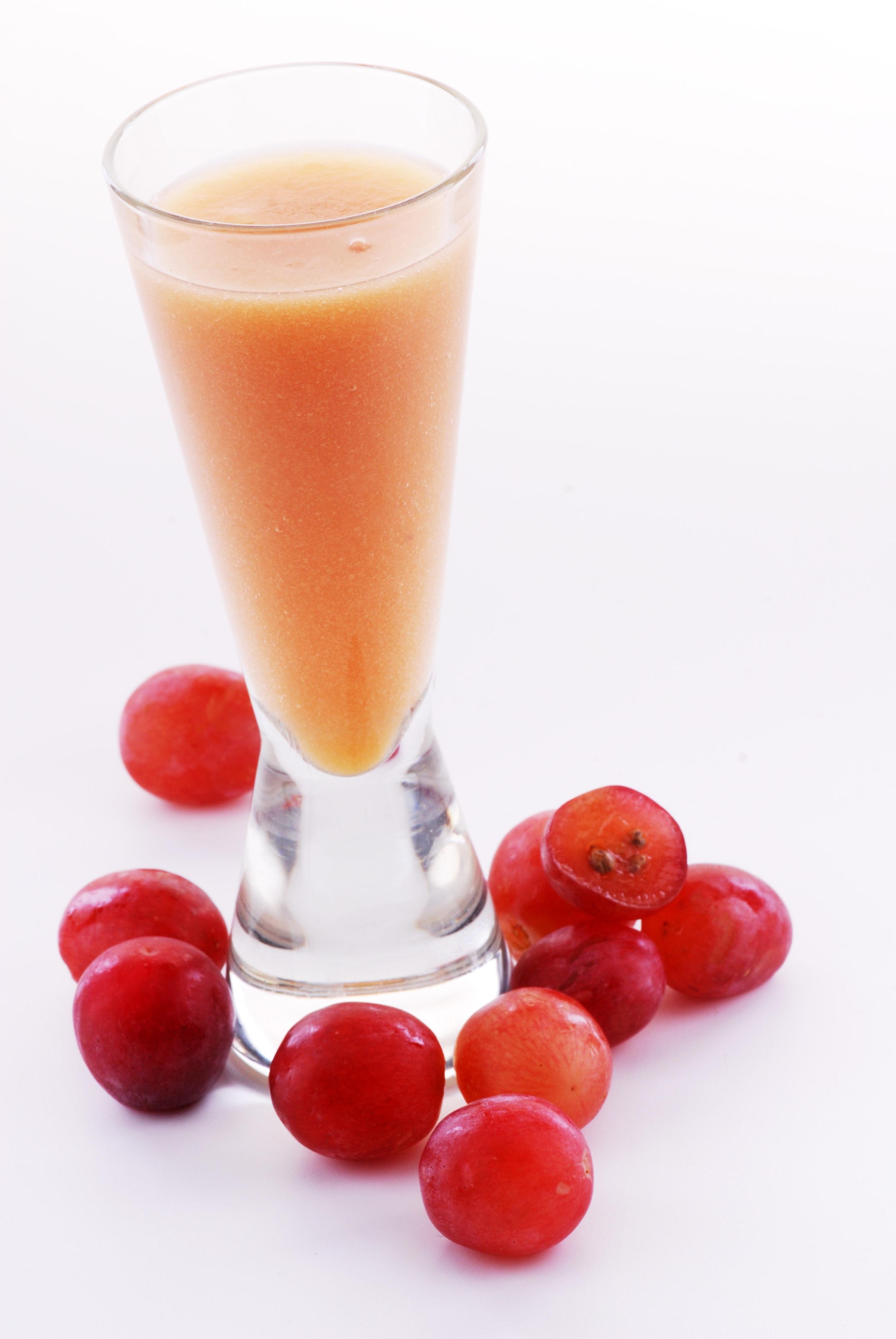 orange juice in clear highball drinking glass near grapes free image