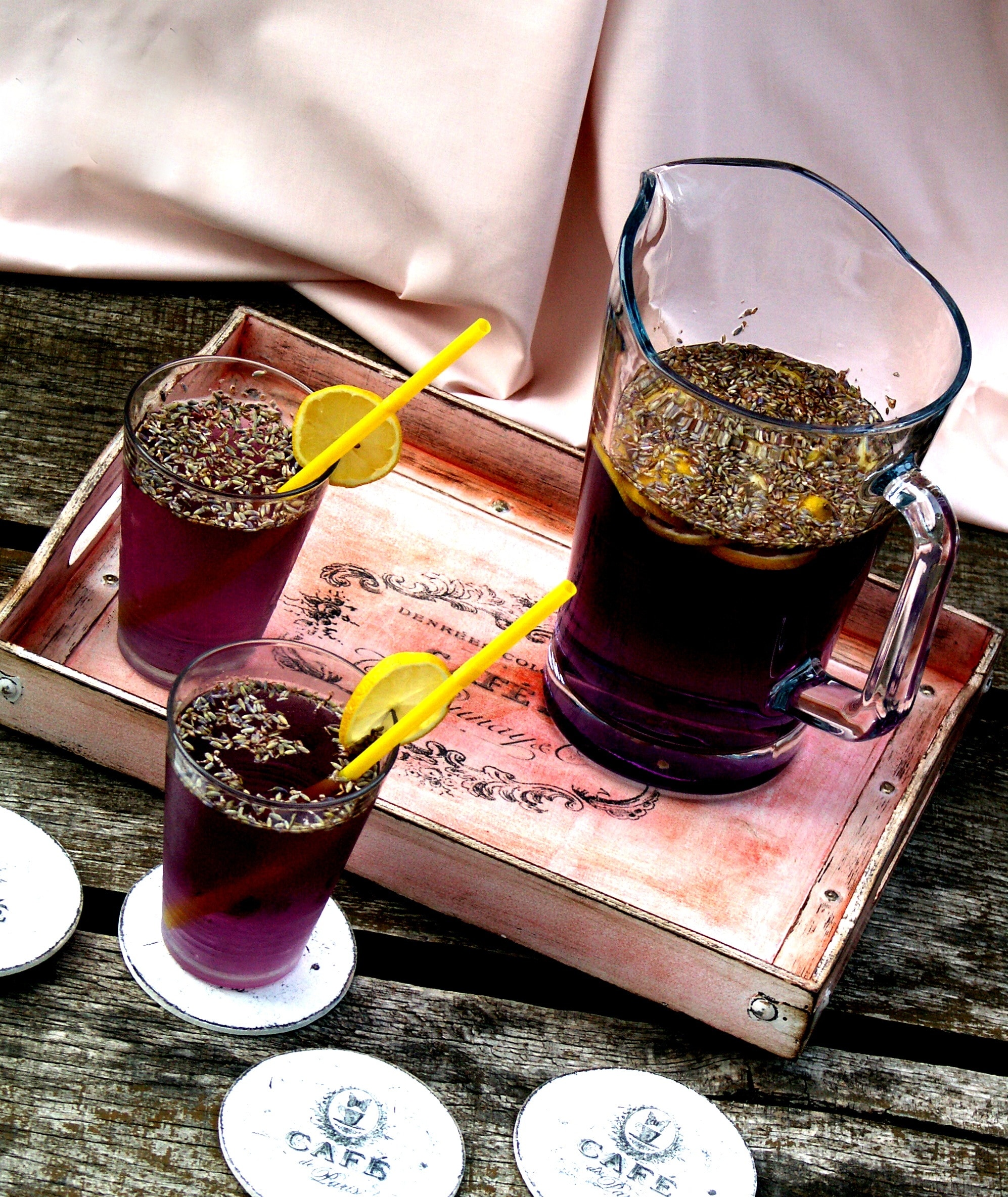 grape juice with slices of lemons and straws near wooden tray
