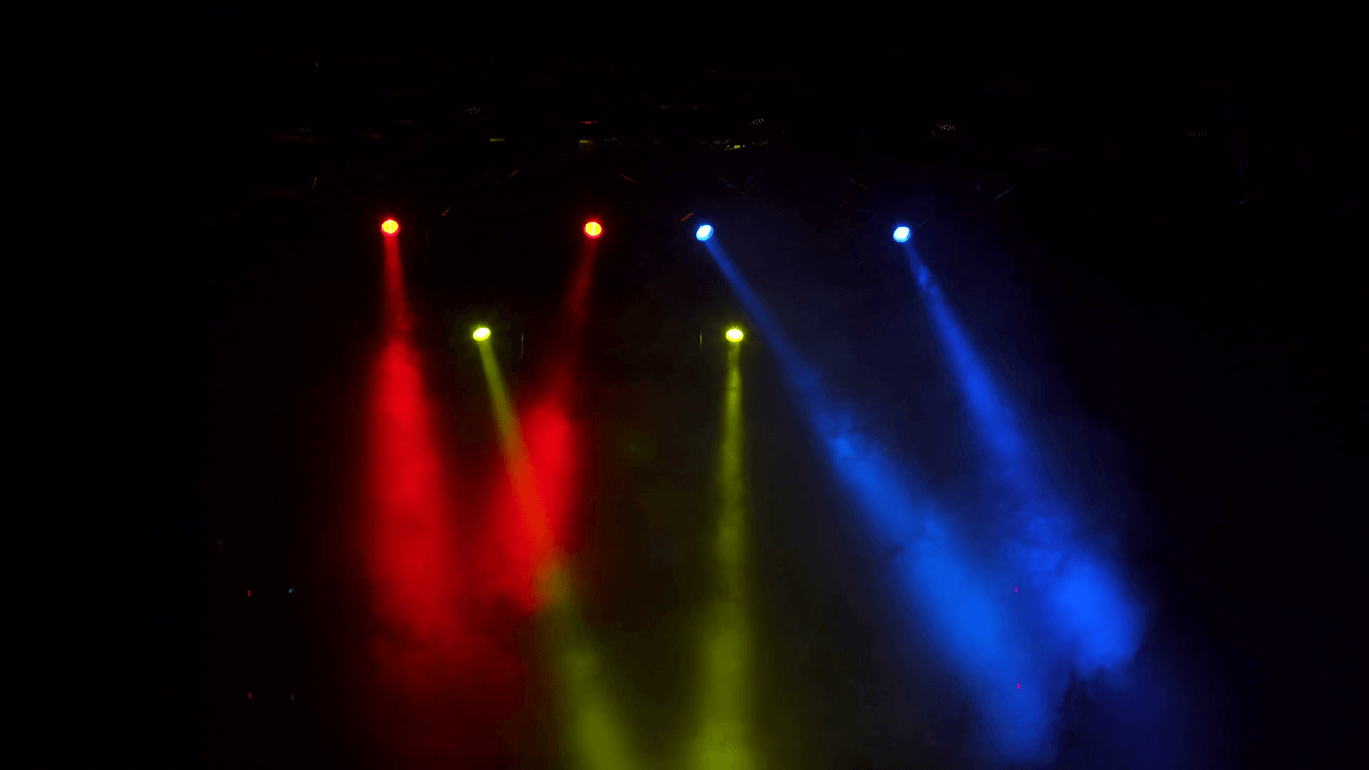 Red, blue and yellow searchlights in smoke on stage. The concert