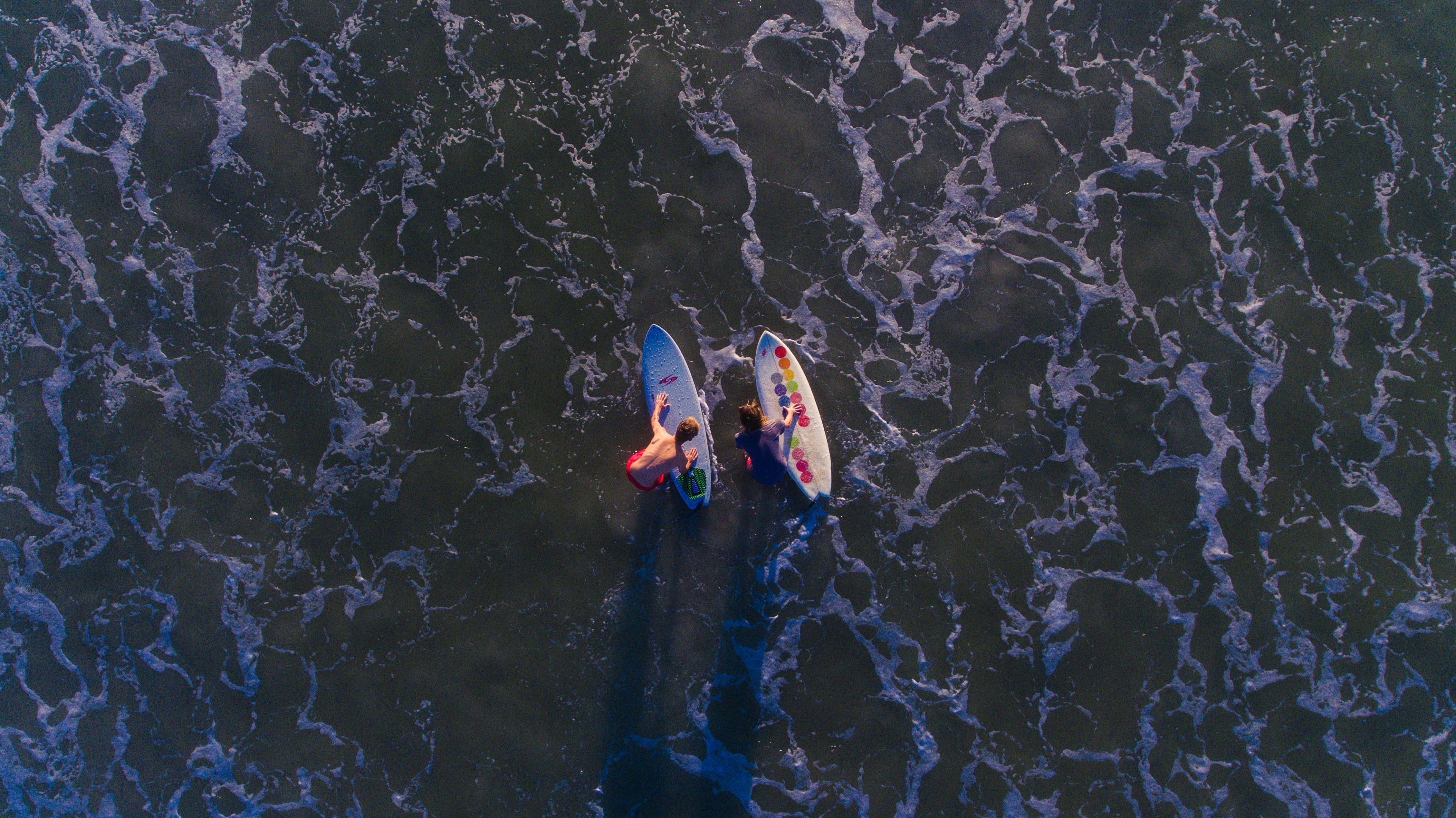 a drone shot aerial view of two surfers on their boards at northside