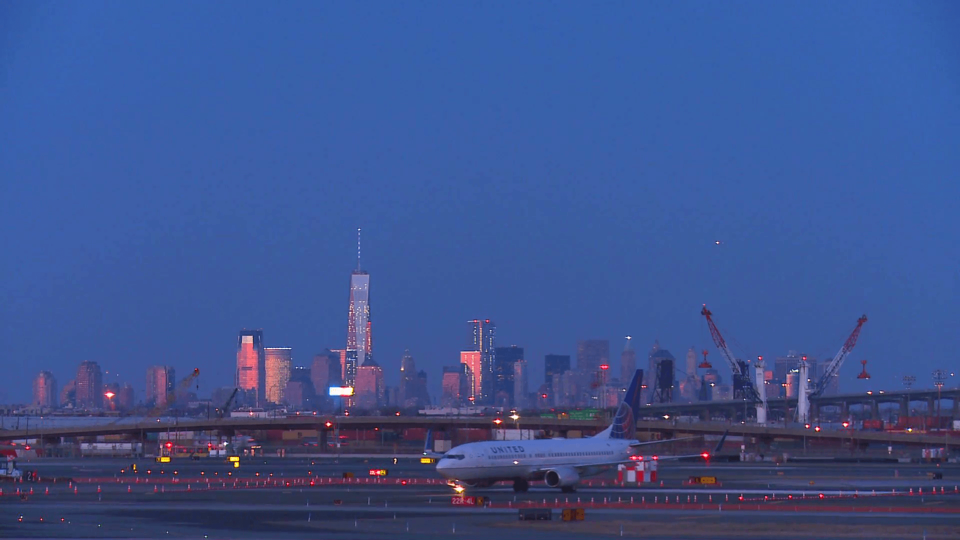 Planes taxi at Newark airport at dusk with the Manhattan skyline