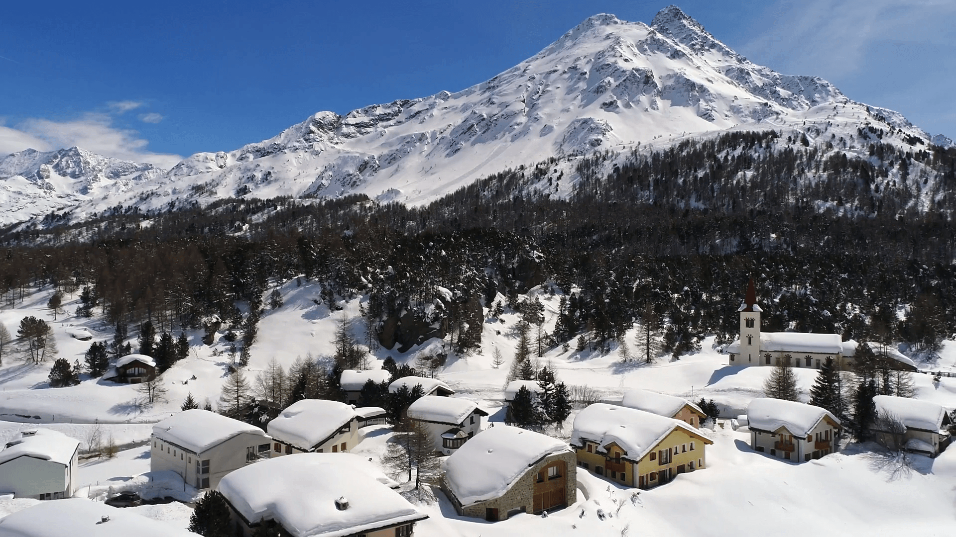 Little village and forest covered with snow. Engadine Valley in