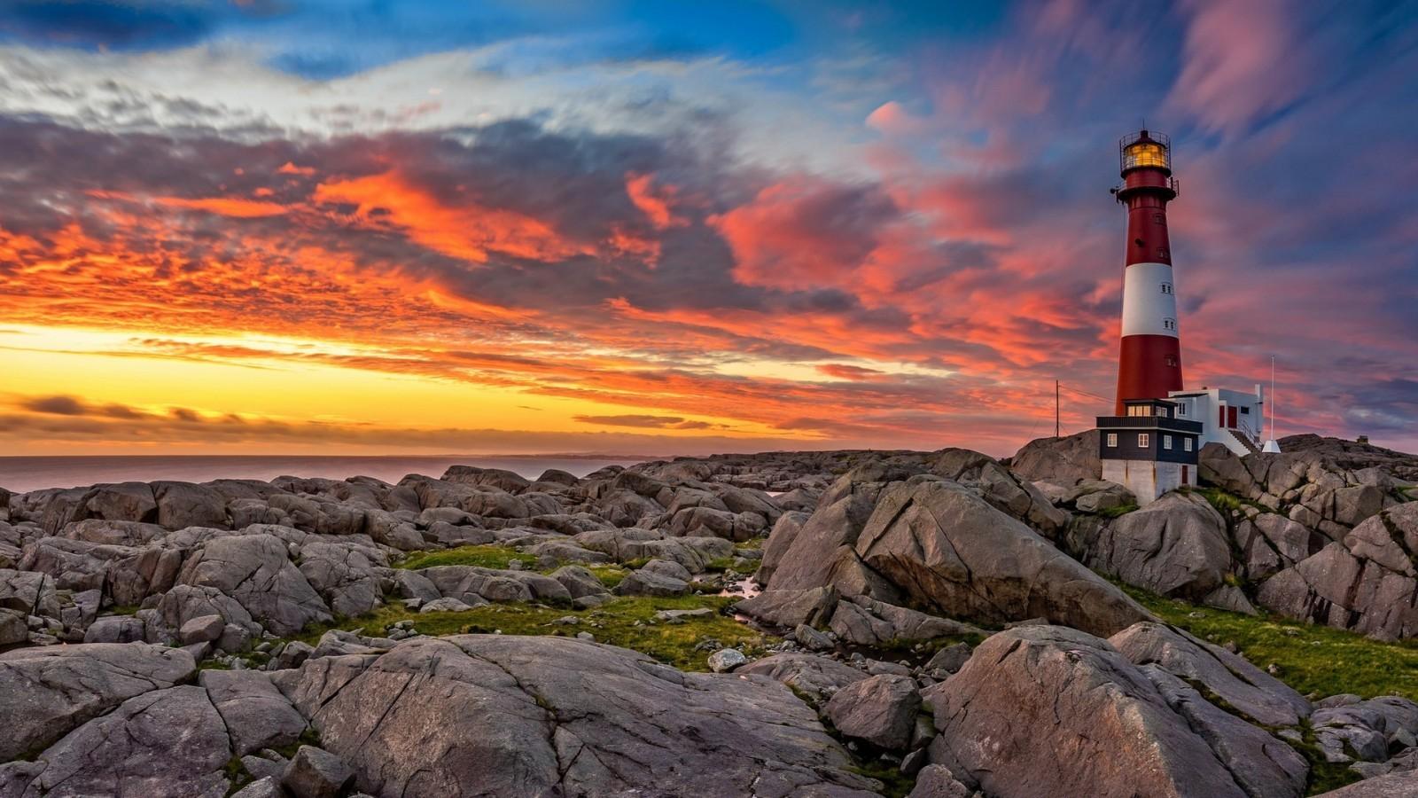 Download 1600x900 Lighthouse, Sunset, Rocks, Clouds Wallpaper