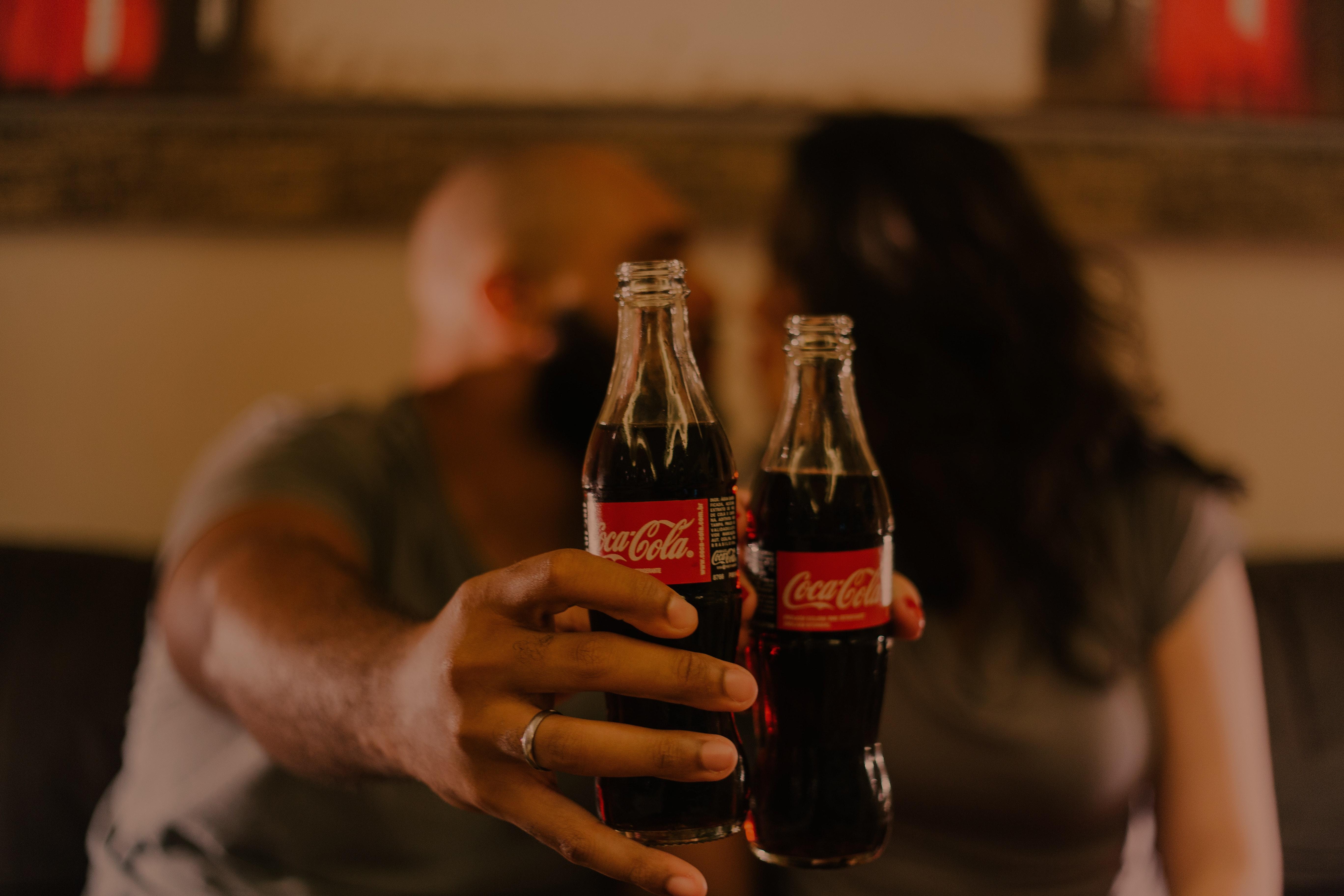 Close Up Photography Of People Holding Coca Cola Bottles · Free
