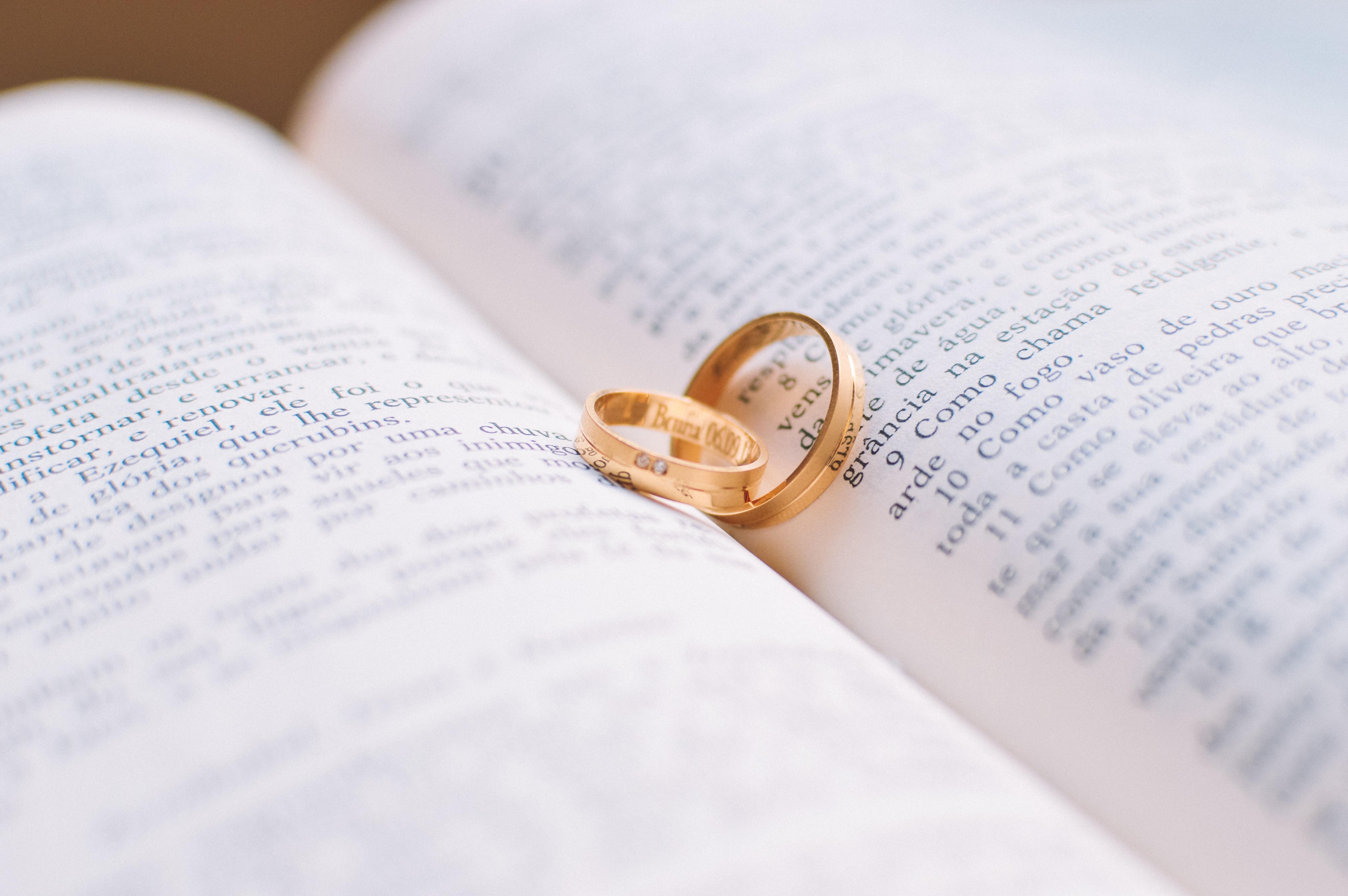 Two Gold Colored Wedding Bands On Book Page · Free