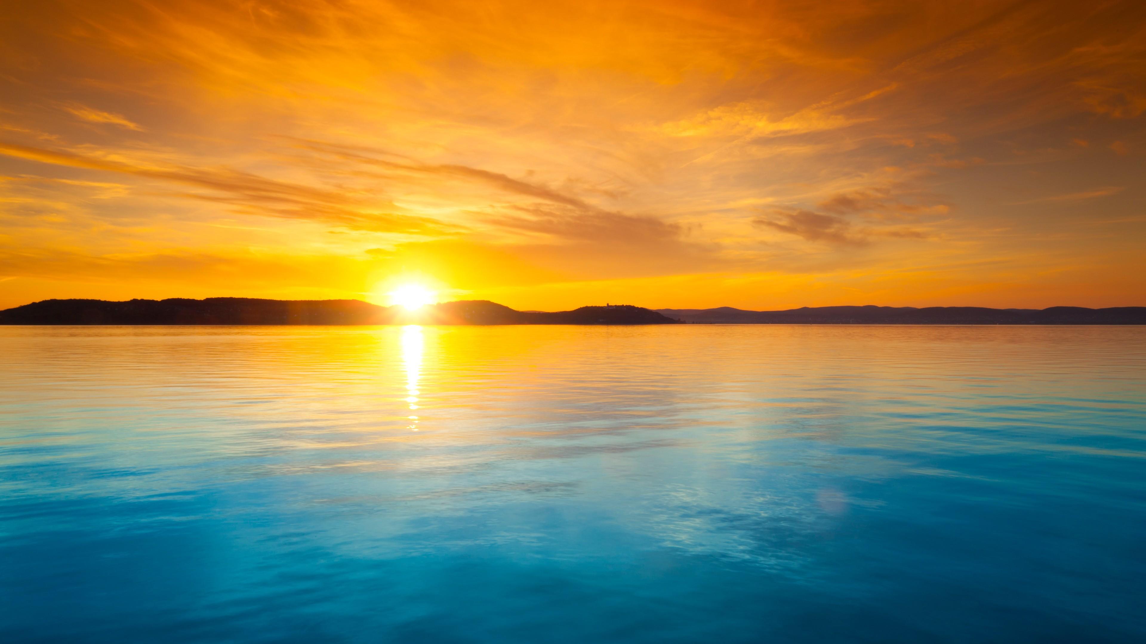 Orange sky over the blue water at sunset wallpaper and image