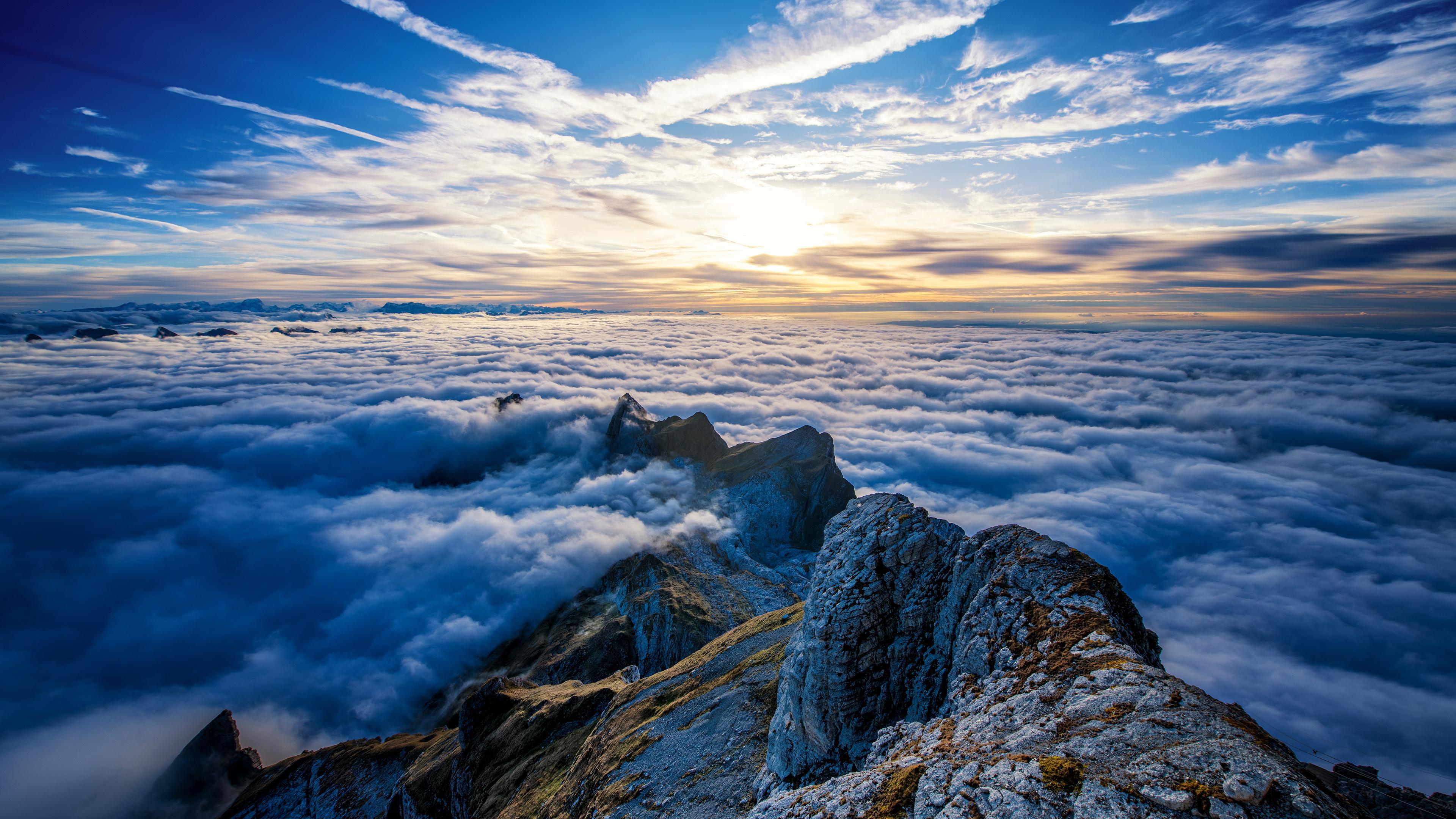 Mountain Peak Above Clouds In Blue Sky With Sun